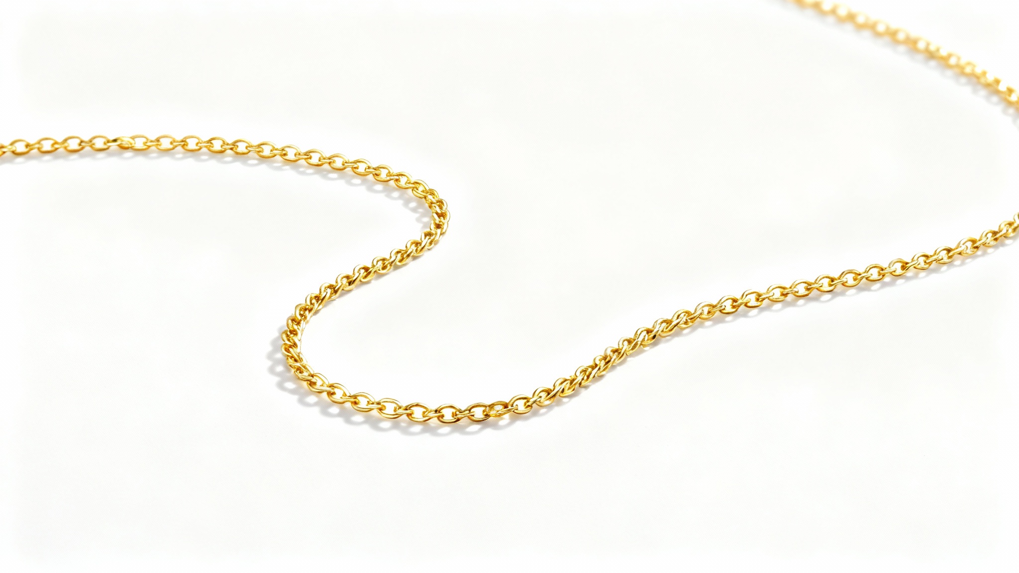 An elegant, high-end product photograph of a delicate gold necklace beautifully arranged on a pure white background, showcasing its fine details and luxurious shine.