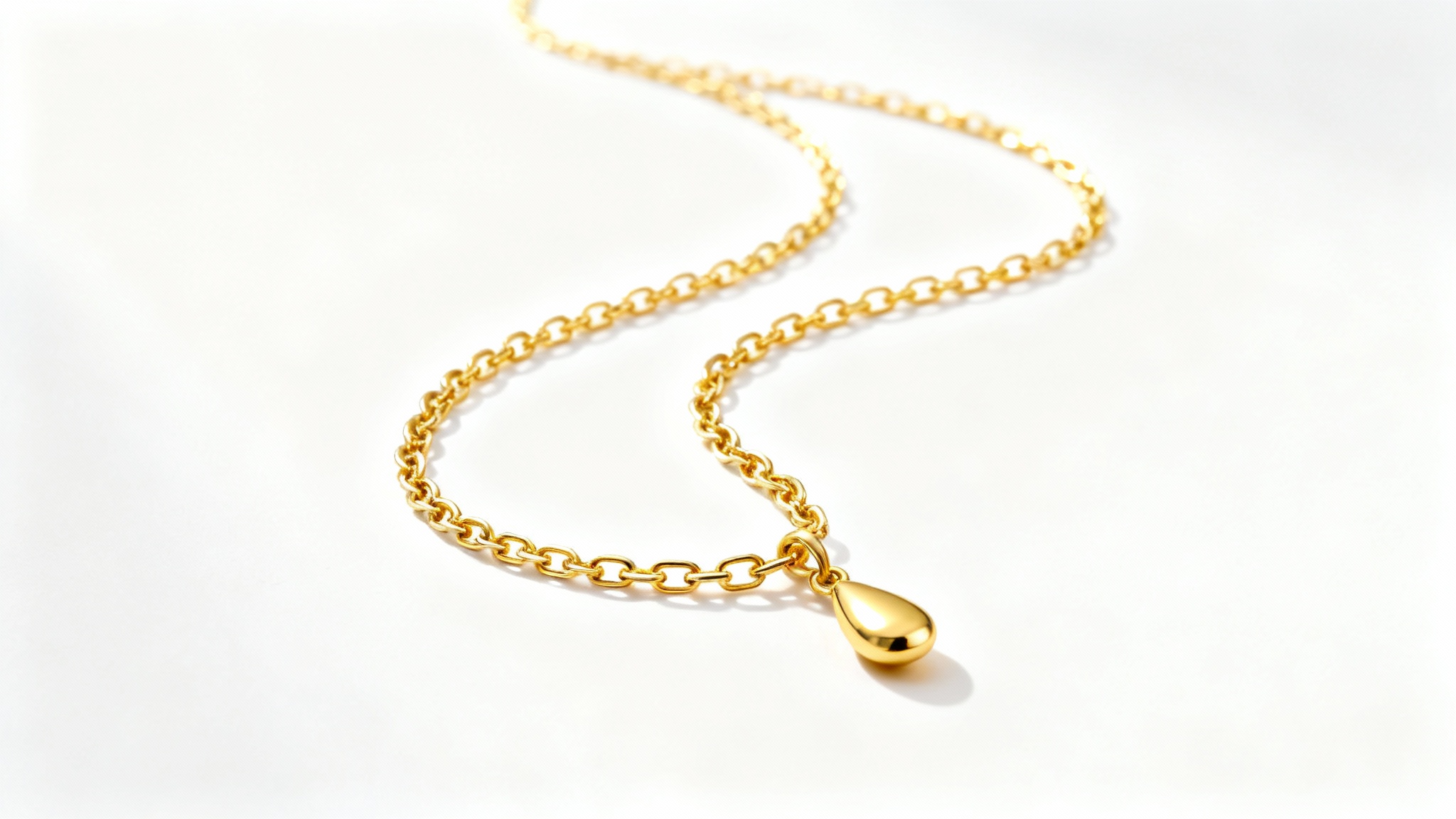 A professional product photograph of a delicate gold necklace with a teardrop pendant, elegantly displayed on a pure white background.