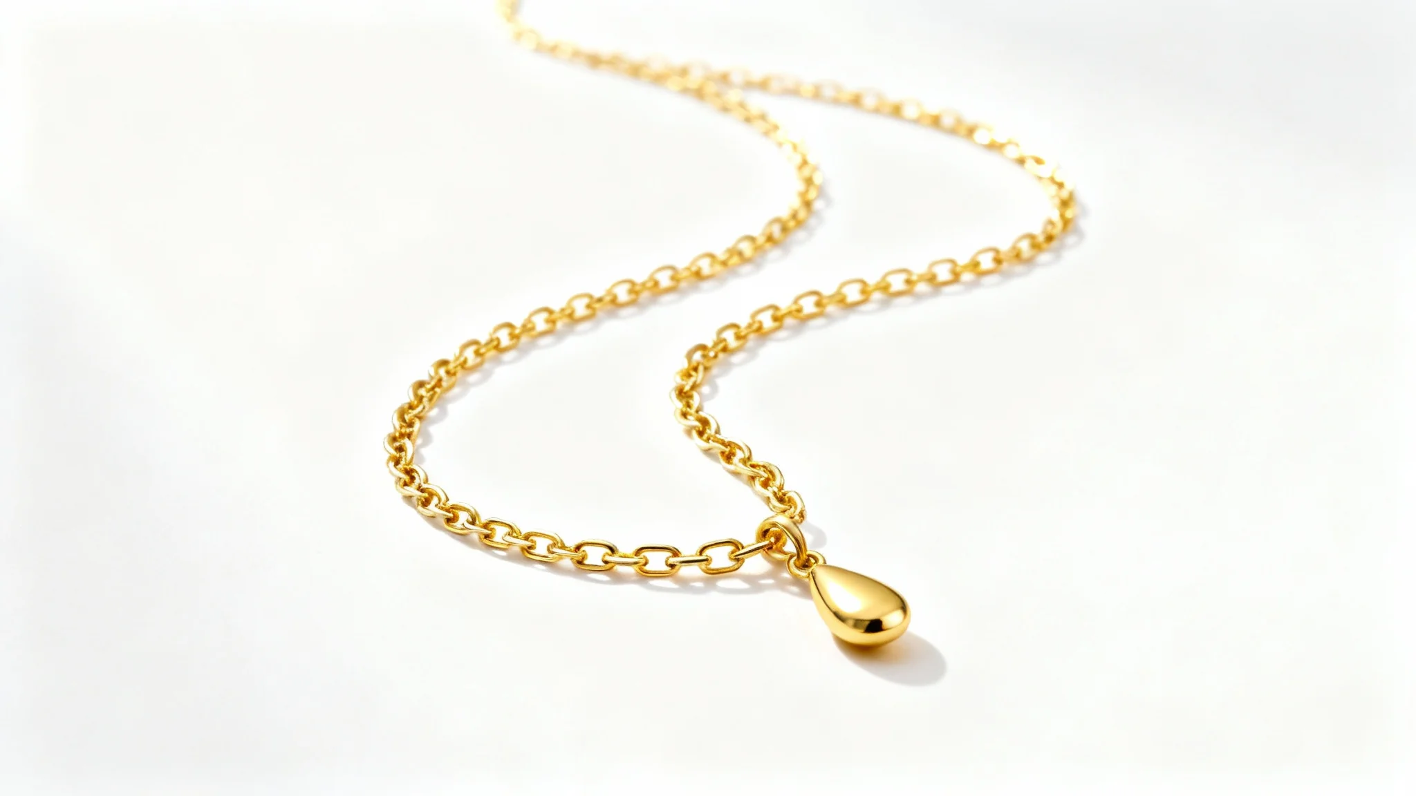 A professional product photograph of a delicate gold necklace with a teardrop pendant, elegantly displayed on a pure white background.