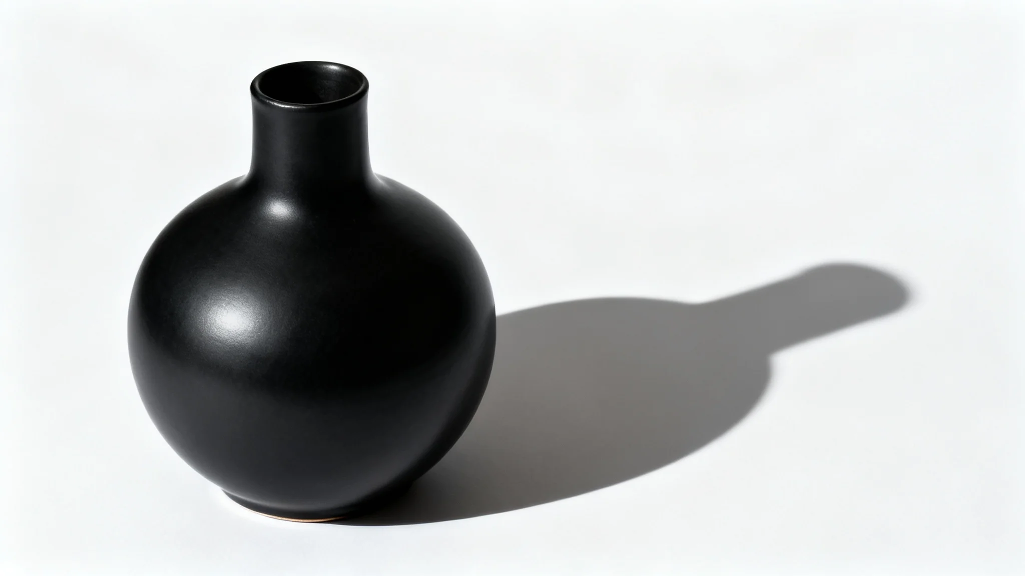 A photorealistic mockup of a modern matte black vase on a white background, casting a long, distinct shadow to showcase a product shadow effect.