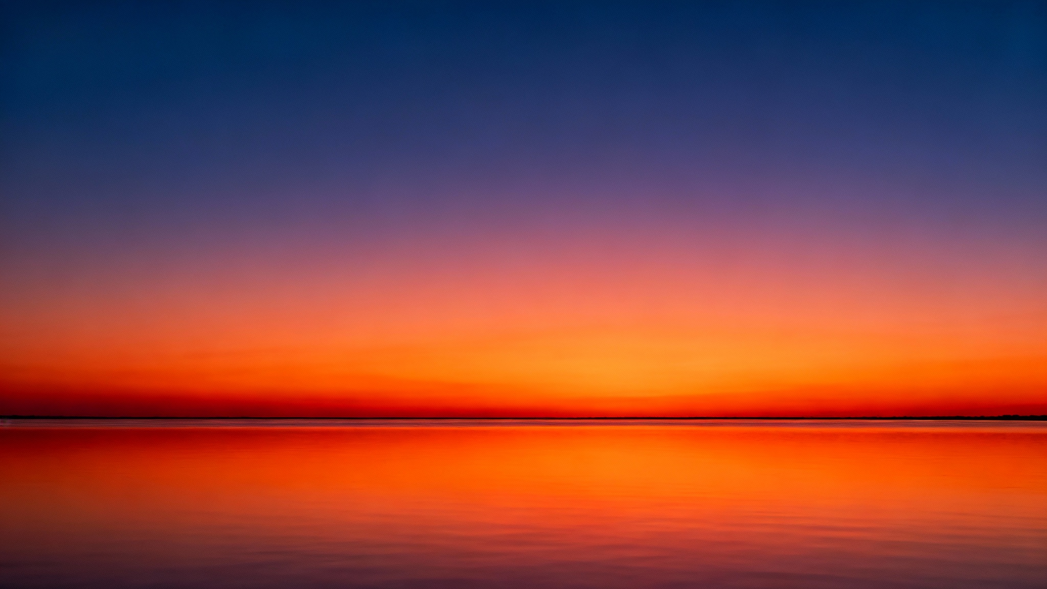 A beautiful, photorealistic image of a sunset over calm water, showcasing a perfectly smooth color gradient in the sky with no visible banding or artifacts.