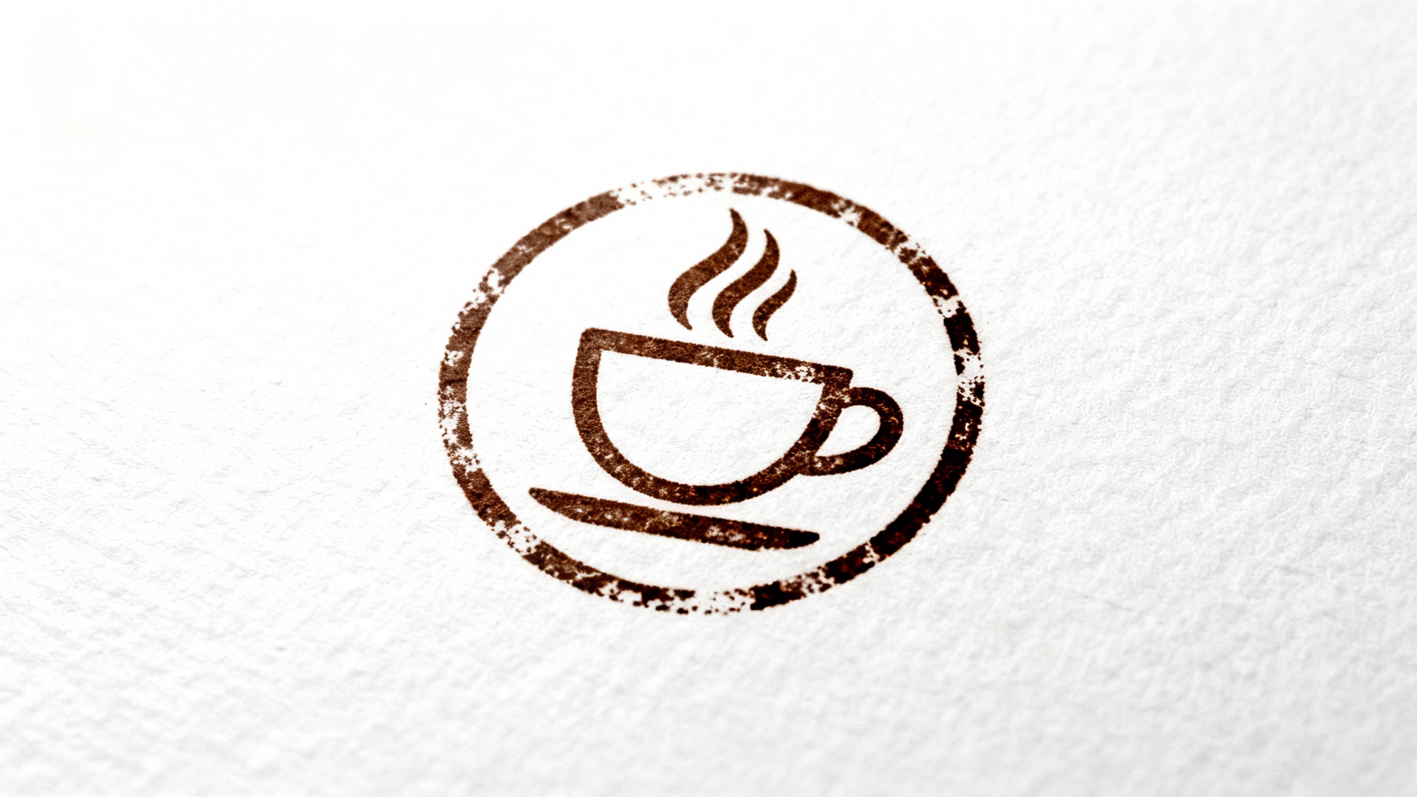 A photorealistic mockup of a circular, dark brown rubber stamp impression on textured white paper. The stamp features a stylized logo of a coffee cup, and the ink has an authentic, slightly weathered texture.