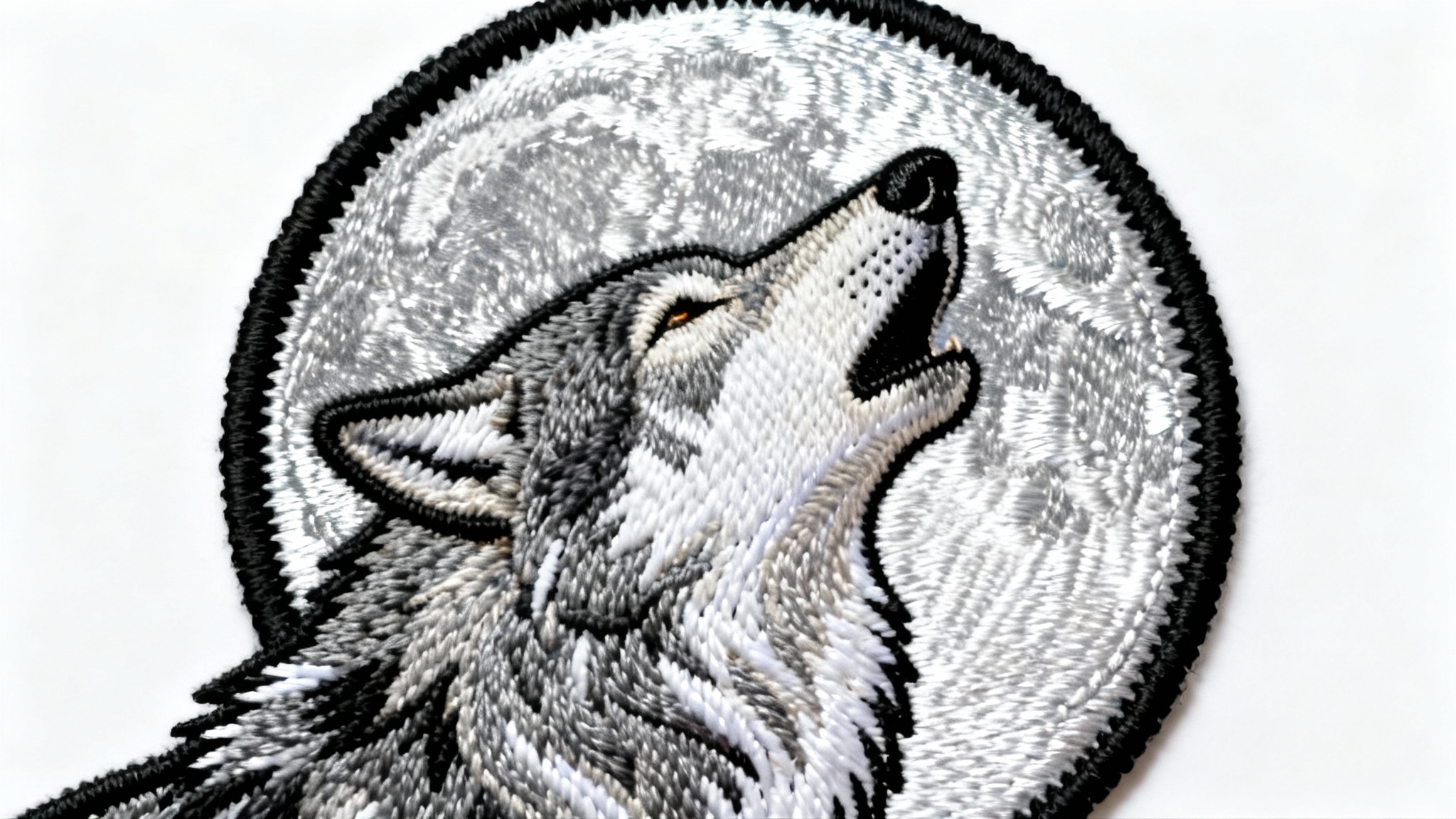 A hyper-realistic, close-up photo of a circular embroidered patch depicting a wolf howling at the moon, showcasing detailed threadwork and texture, set against a plain white background.