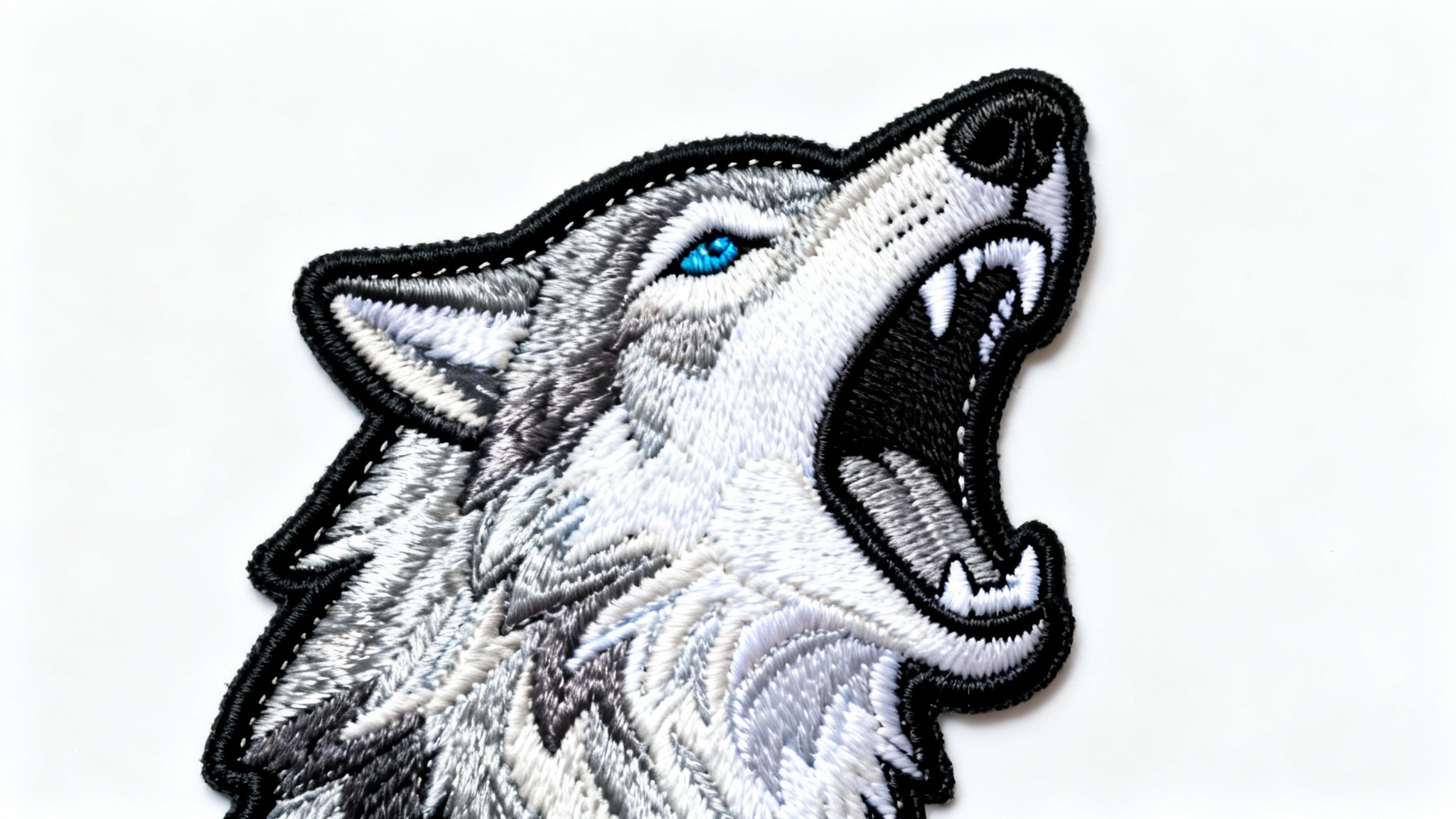 A highly detailed embroidered patch of a howling wolf's head, showcasing intricate threadwork and texture, set against a plain white background.