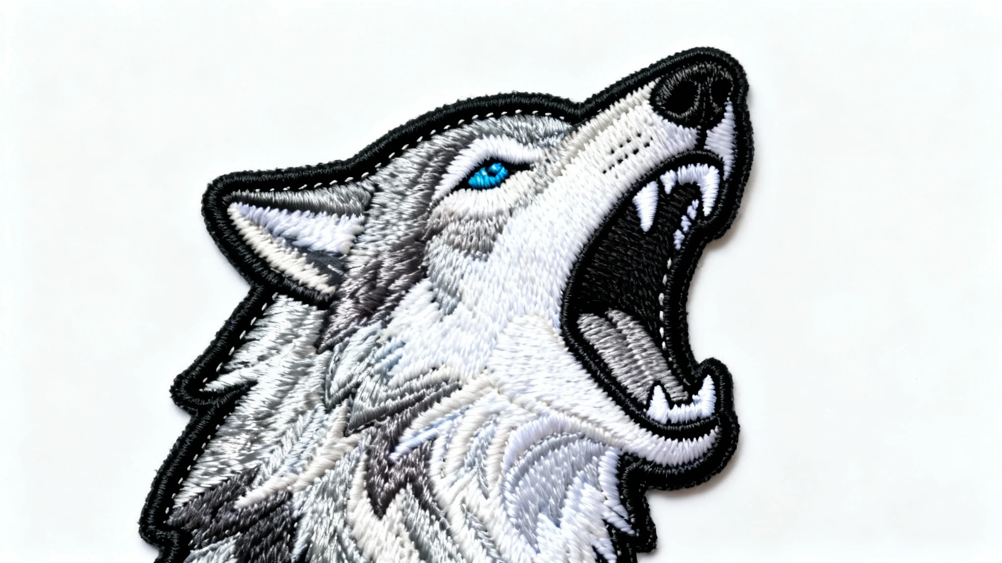 A highly detailed embroidered patch of a howling wolf's head, showcasing intricate threadwork and texture, set against a plain white background.