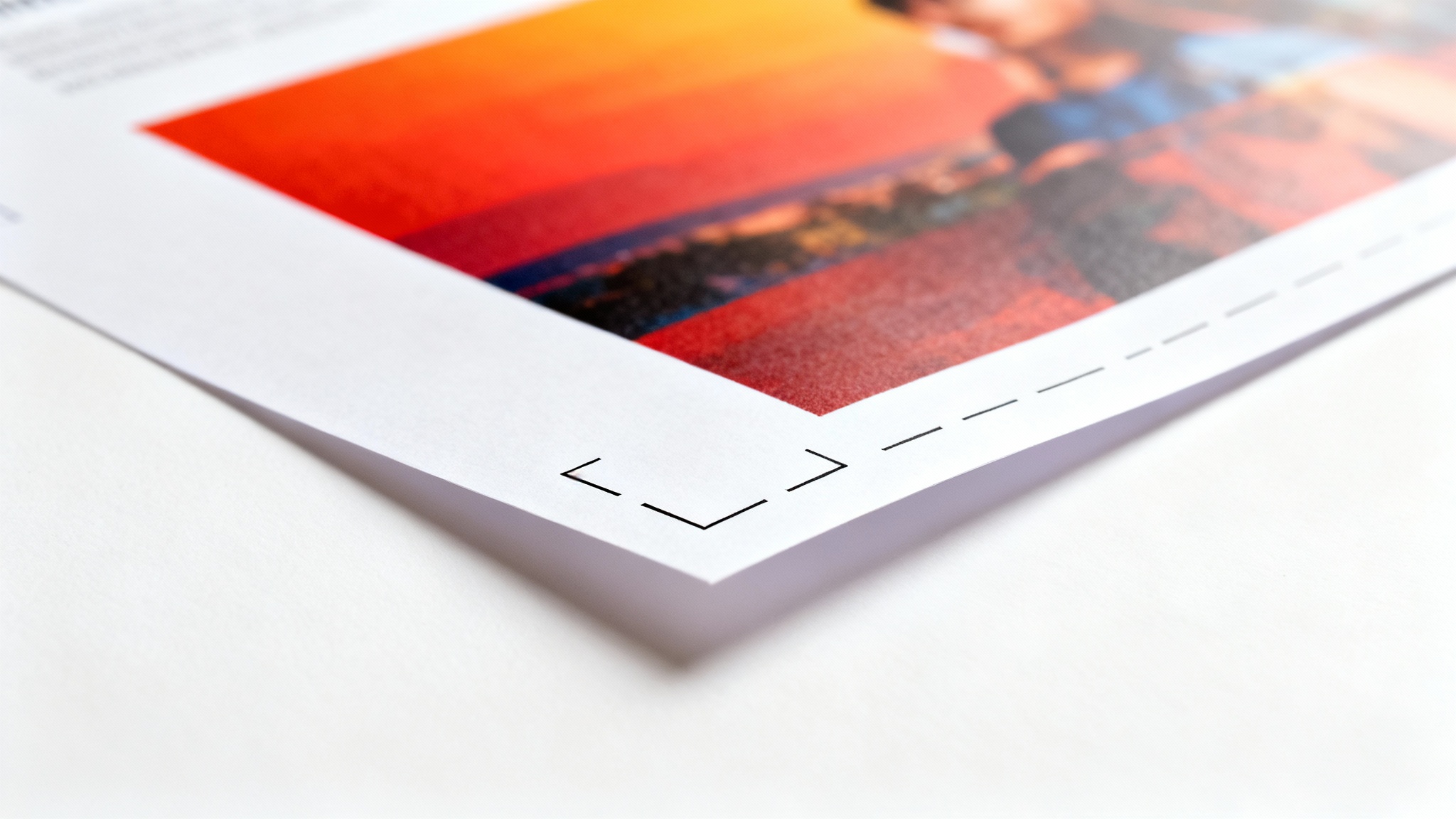 A close-up, photorealistic image of the corner of a printed flyer on a white background, illustrating a print bleed. A vibrant design extends past the black crop mark, showing the area that will be trimmed off.