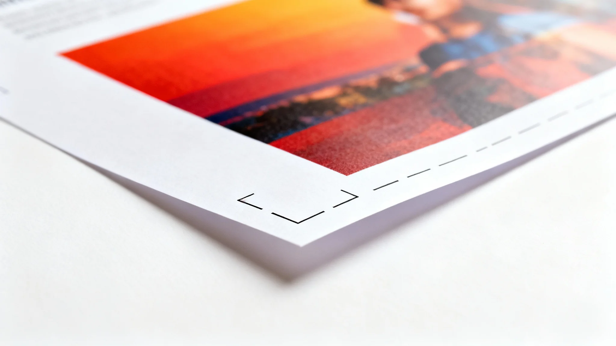 A close-up, photorealistic image of the corner of a printed flyer on a white background, illustrating a print bleed. A vibrant design extends past the black crop mark, showing the area that will be trimmed off.