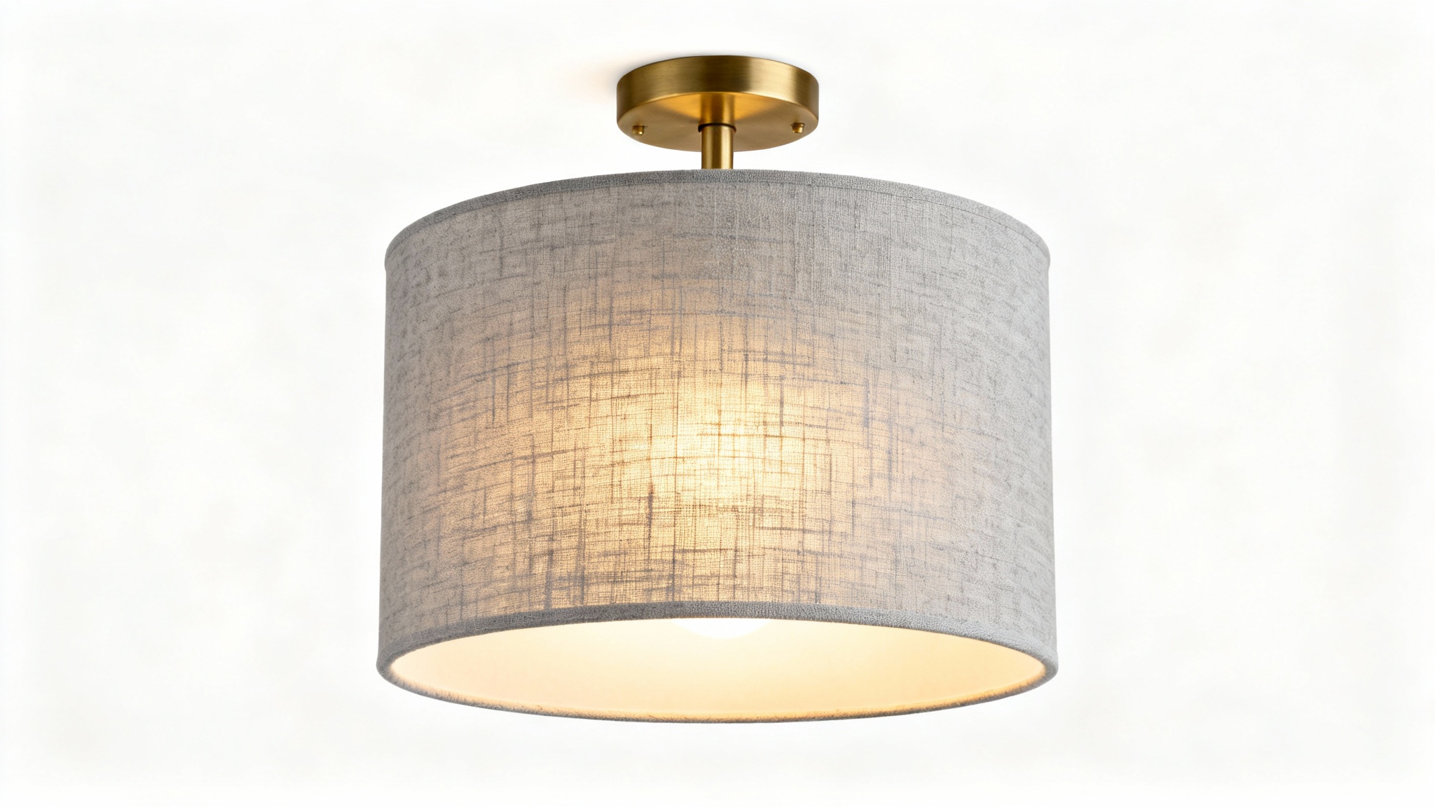 A modern semi-flush drum light with a textured gray linen shade and brushed brass hardware, illuminated and centered against a plain white background.