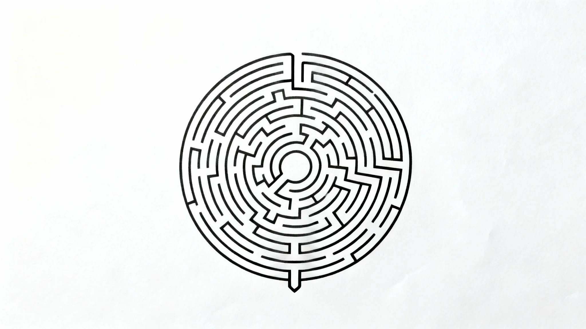 A black and white circular maze on a plain white background, featuring a complex pattern of paths from an entrance to an exit.