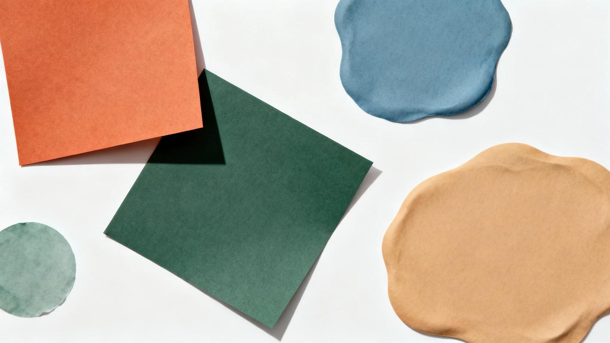 An artistic flat lay of color swatches in terracotta, sage green, dusty blue, and sand, arranged in various shapes on a clean white background to represent a generated color palette.