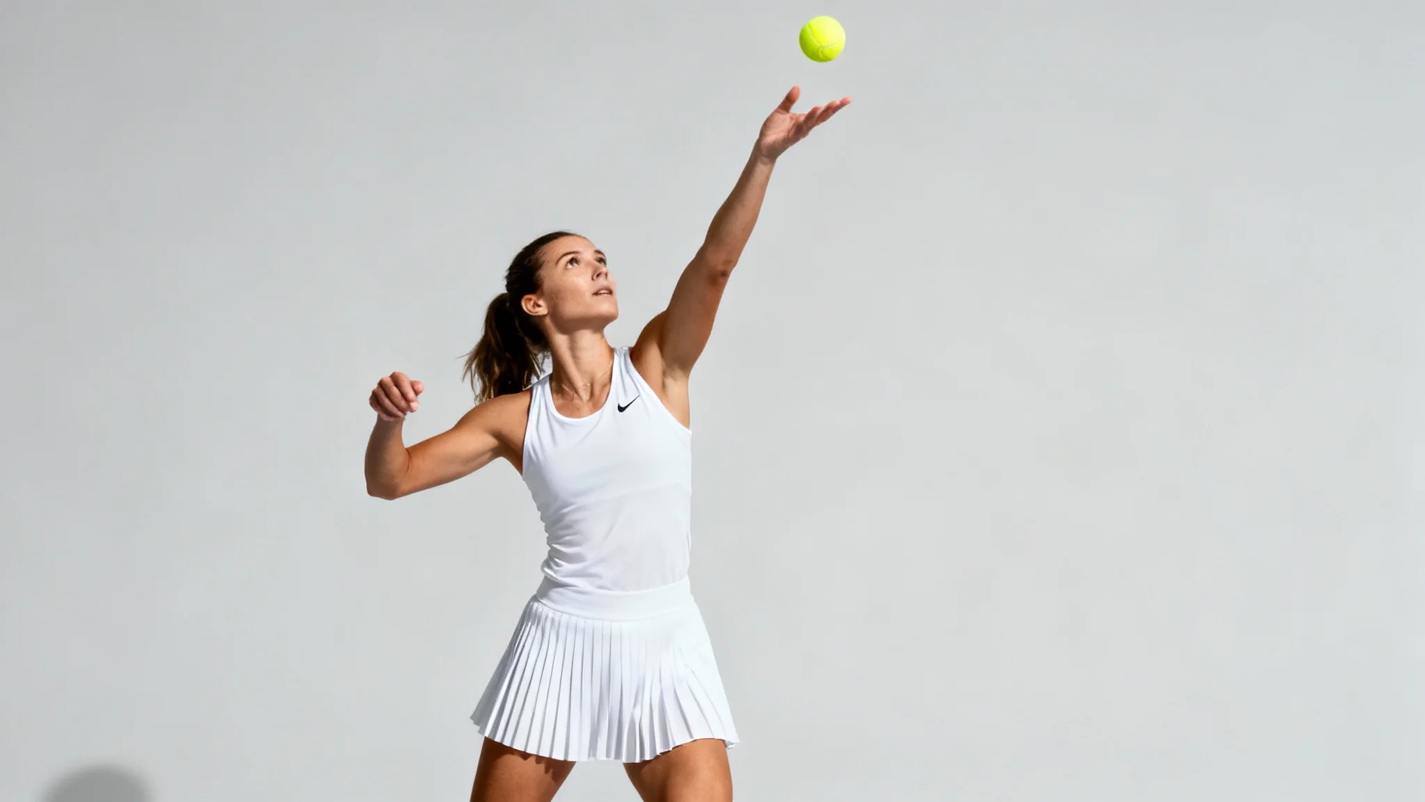 A photorealistic image of a female tennis player in mid-serve, dressed in white athletic wear, tossing a tennis ball against a clean, light gray background.