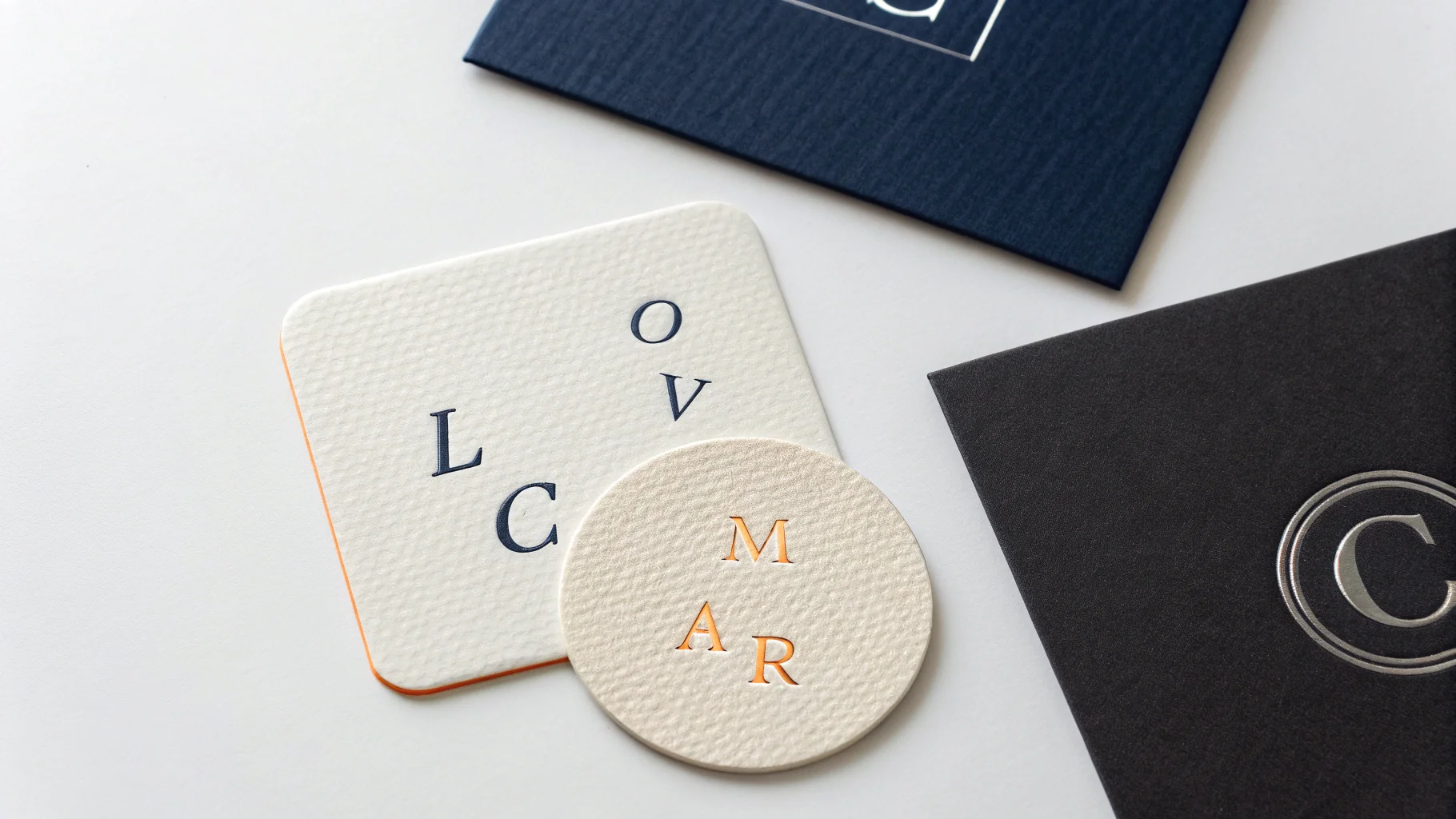 A collection of different monogram logos mocked up on various materials like a business card, paper, and leather, demonstrating diverse styles for branding on a white background.