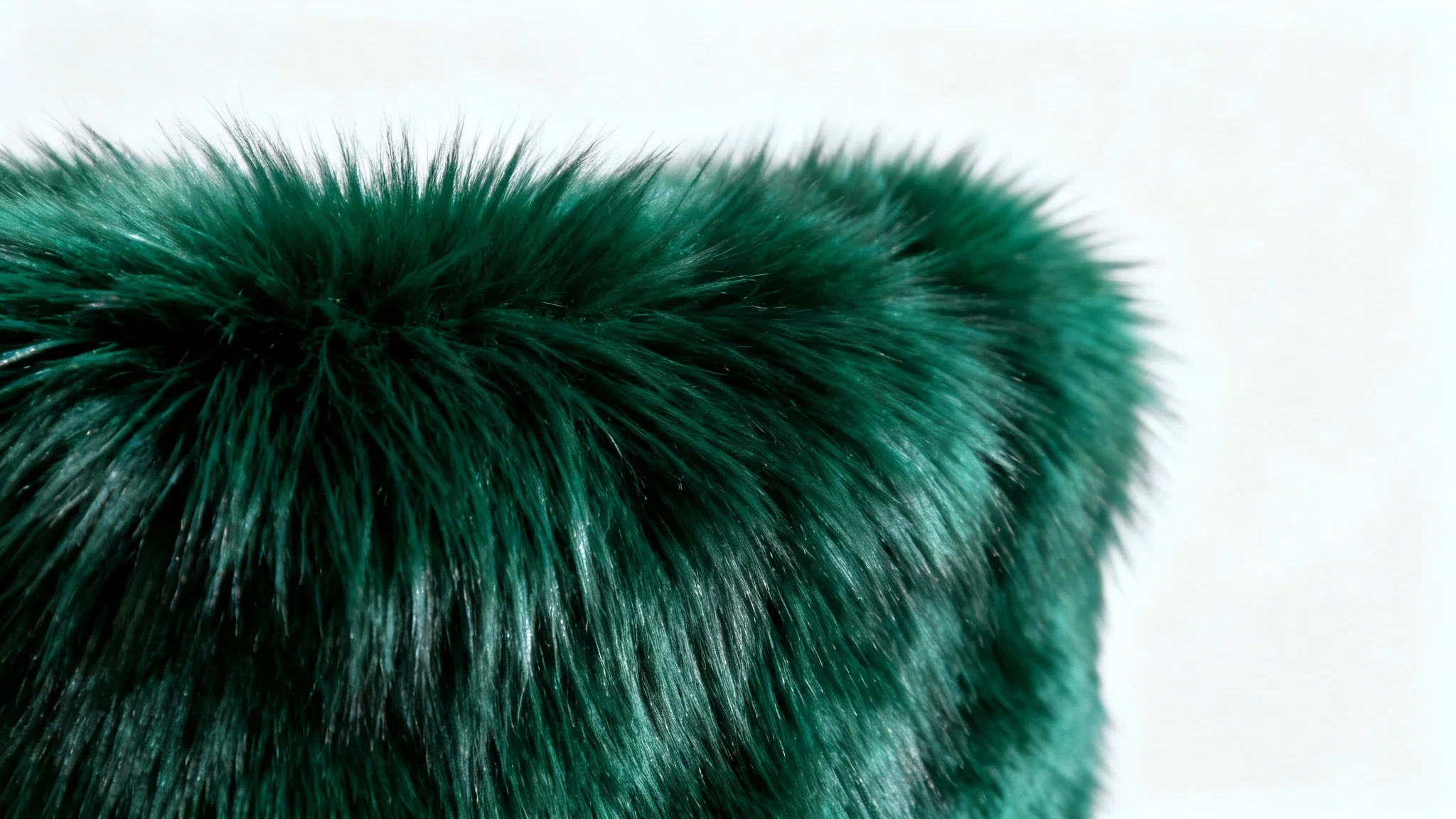 An extreme close-up, photorealistic shot of a luxurious emerald green faux fur texture, showcasing its soft, dense fibers and plush quality against a clean white background.