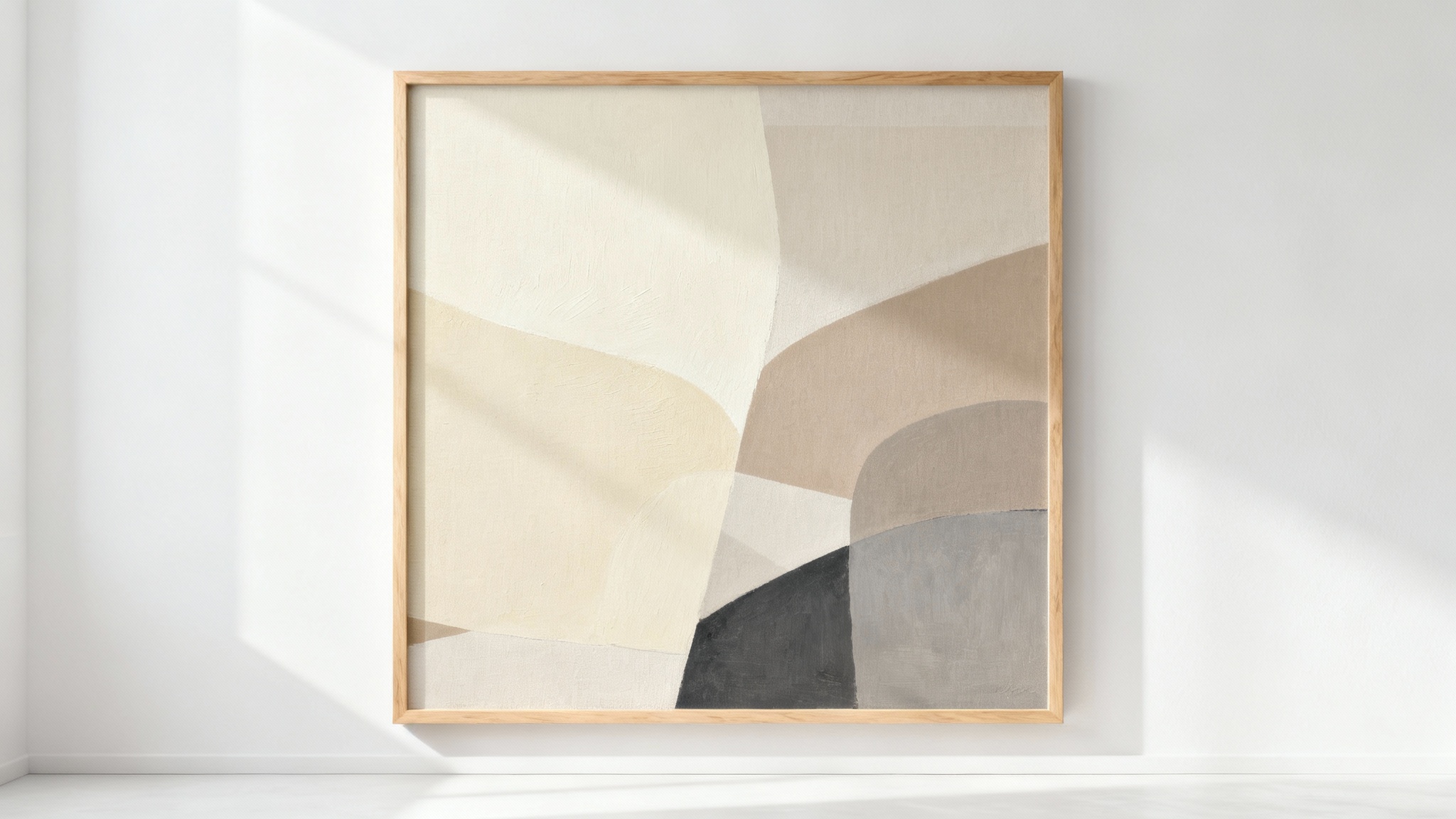 A framed piece of neutral abstract wall art with beige, cream, and grey tones, mounted on a clean white wall in a studio setting.