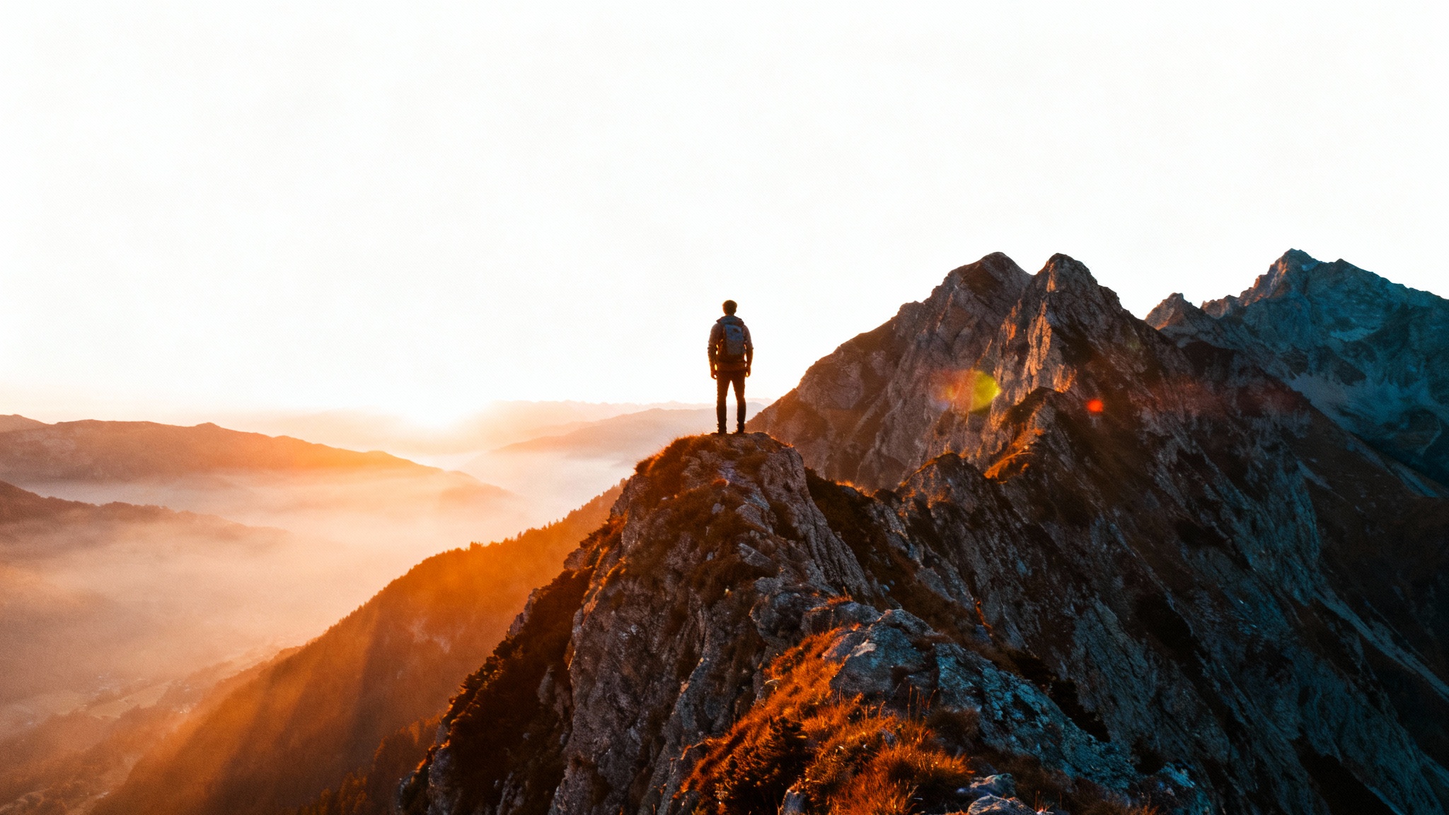 A photorealistic, cinematic still of a lone hiker standing on a mountain peak at sunrise, looking out over misty valleys. The image has a professional, movie-like quality.