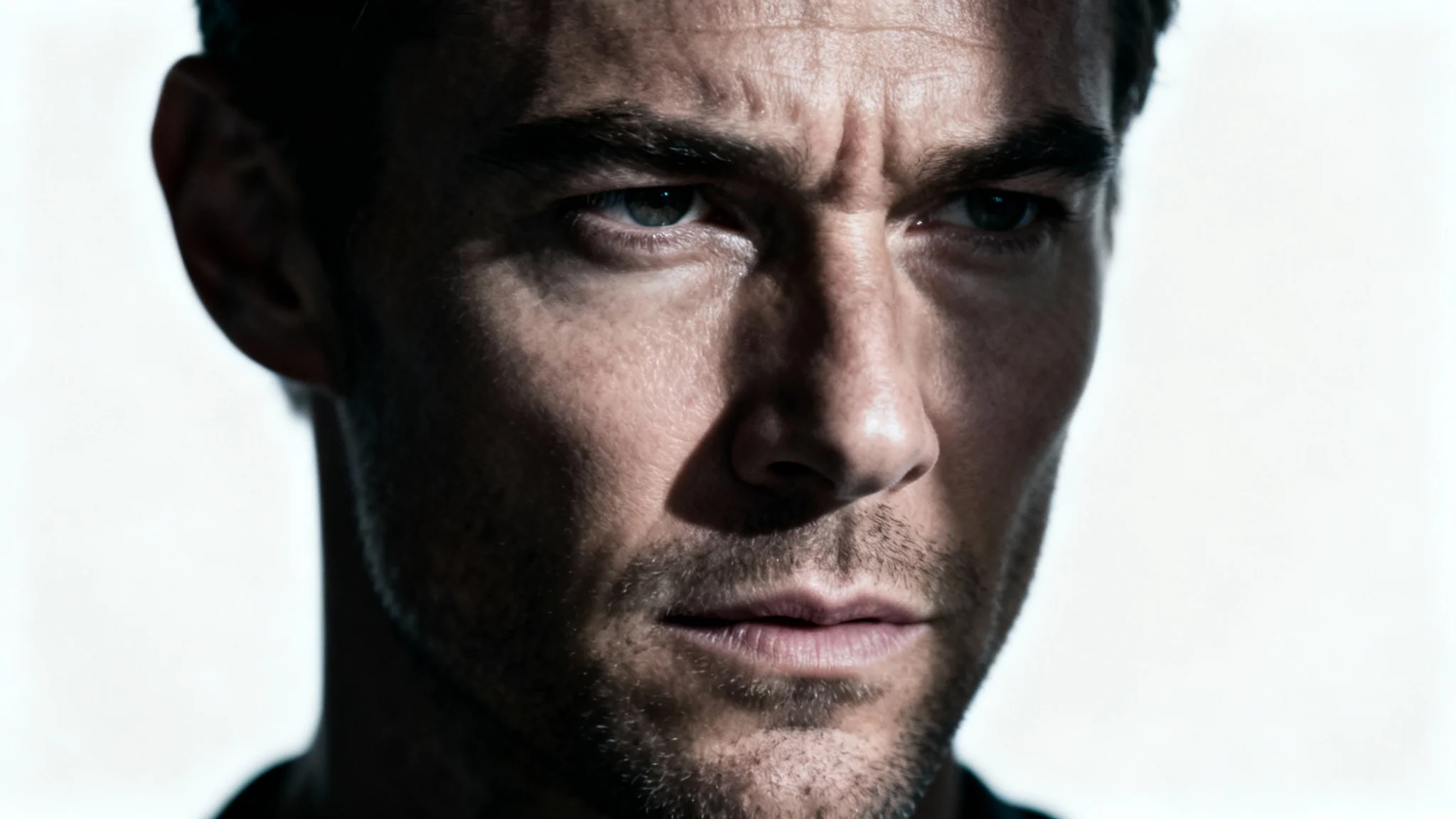 A dramatic, cinematic-style close-up portrait of a man's face with high-contrast lighting, resembling a still frame from a movie, set against a white background.