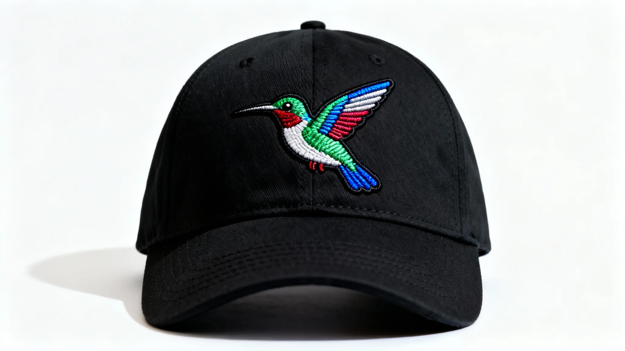 A stylish black cotton baseball cap featuring a vibrant, detailed embroidery of a hummingbird, presented as a product mockup on a plain white background.