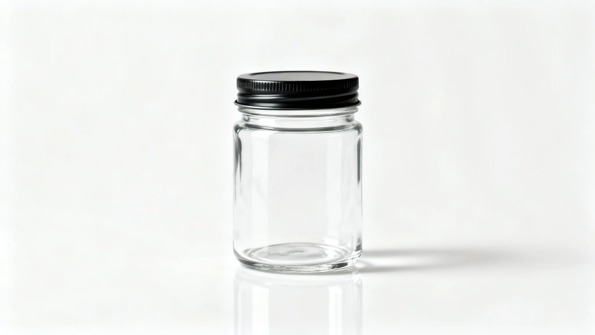 A photorealistic mockup of a clean, empty glass jar with a black lid, set against a plain white background, ready for a product label.