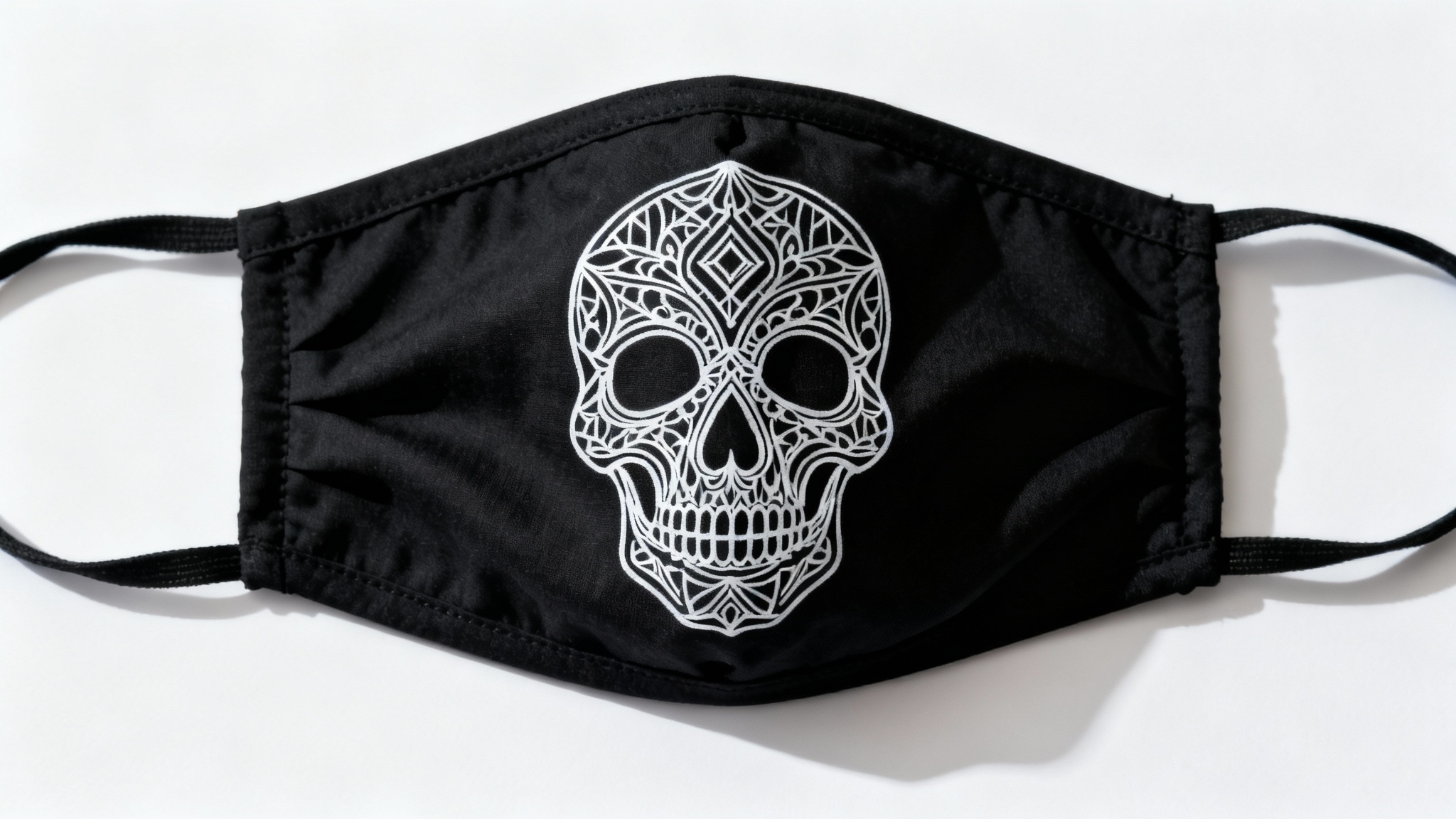 A black fabric mask with a white line art pattern of a stylized skull, shown flat against a clean white background in a product-style photo.
