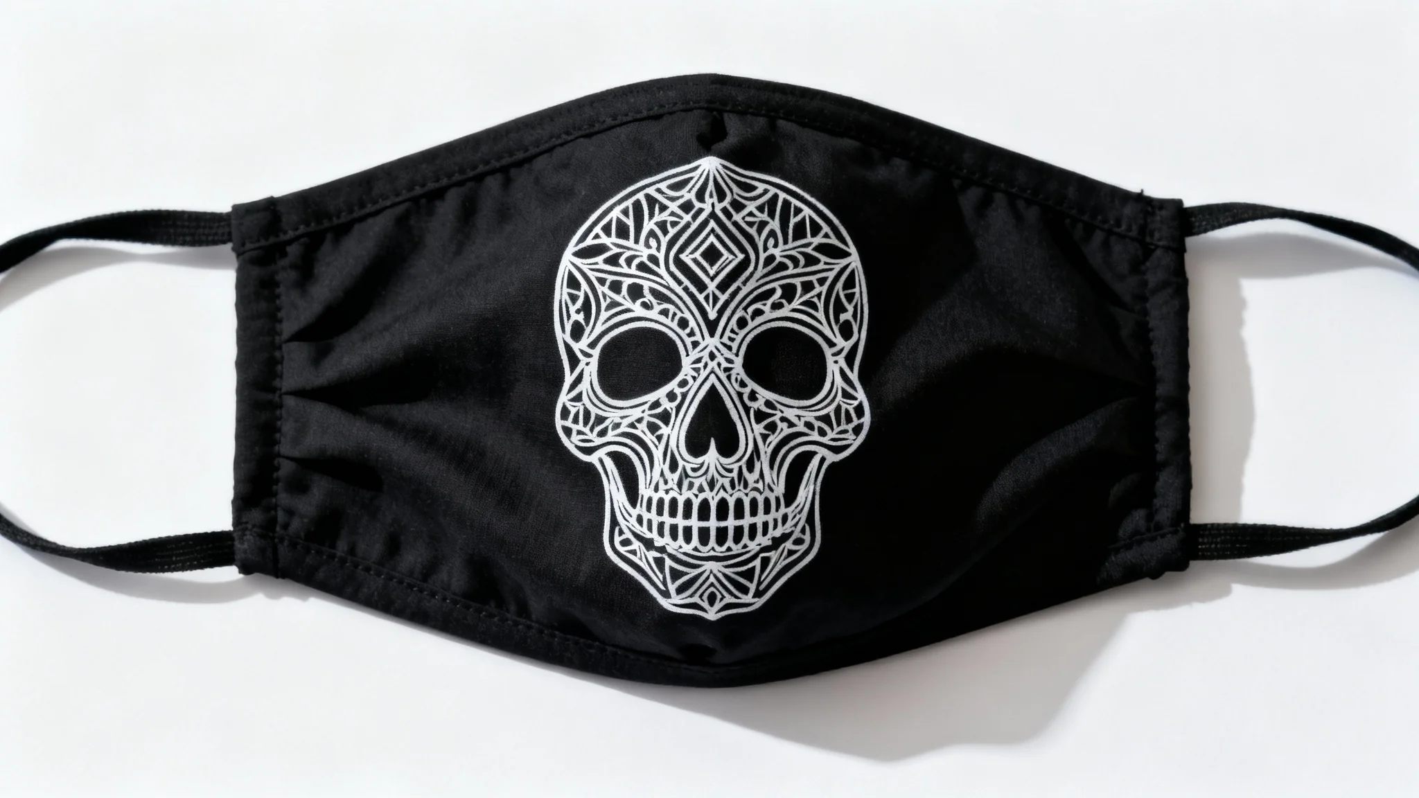 A black fabric mask with a white line art pattern of a stylized skull, shown flat against a clean white background in a product-style photo.