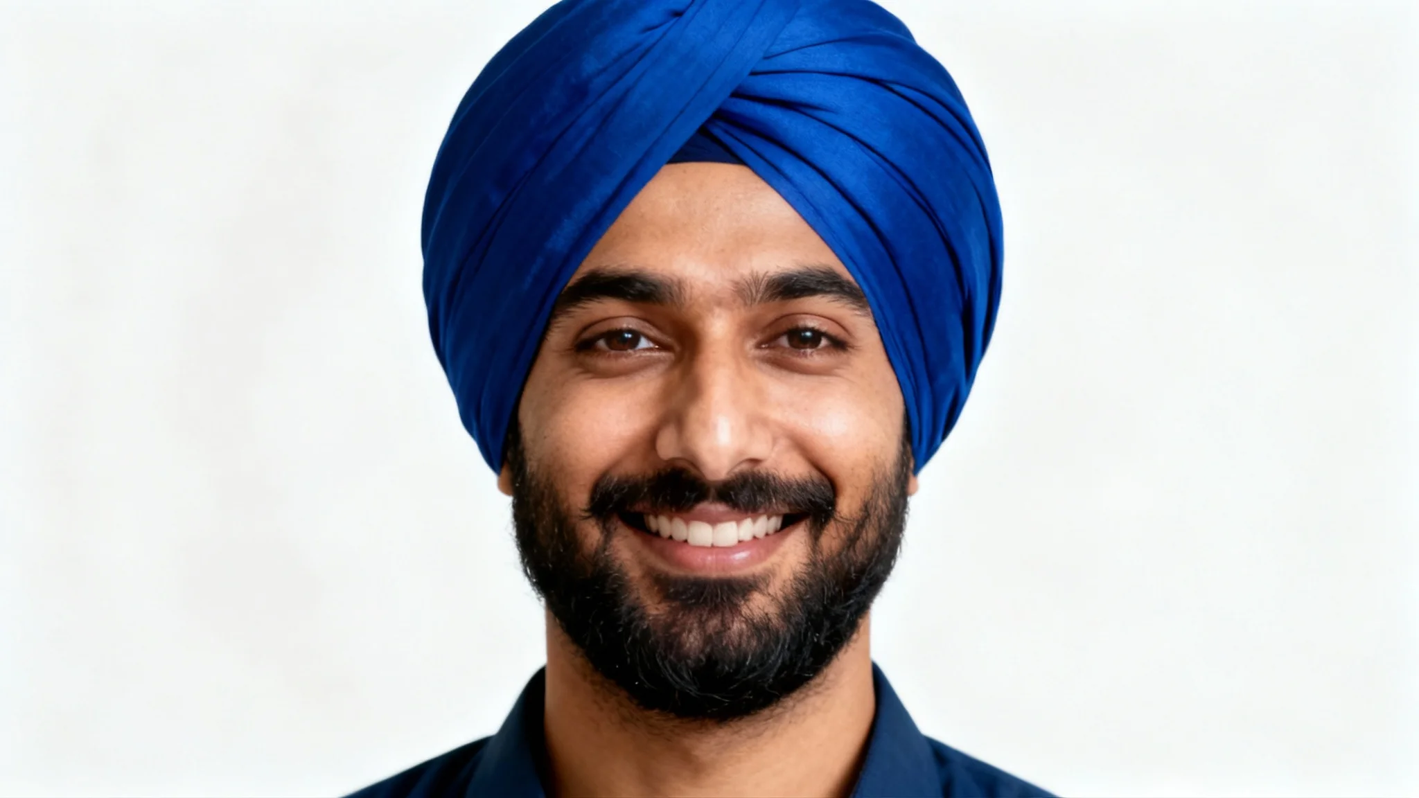 A photorealistic portrait of a smiling South Asian man with a beard wearing a vibrant royal blue turban, set against a clean white background.