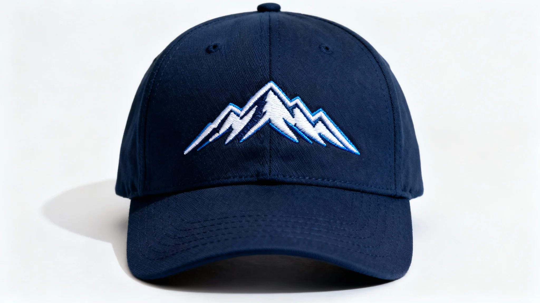 A professional mockup of a dark navy blue baseball cap on a white background, featuring a detailed, high-quality embroidery of a stylized white and blue mountain range on the front.