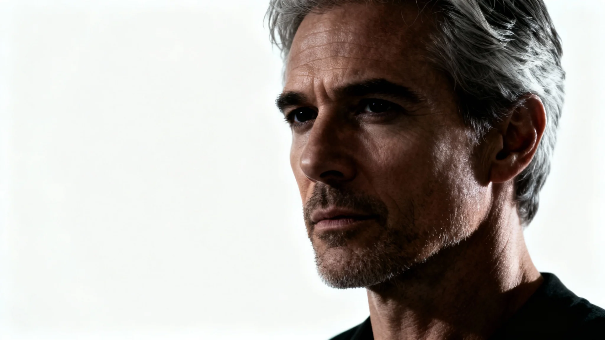 A dramatic, cinematic portrait of a man with intense eyes and moody side-lighting, presented as a mockup against a stark white background.