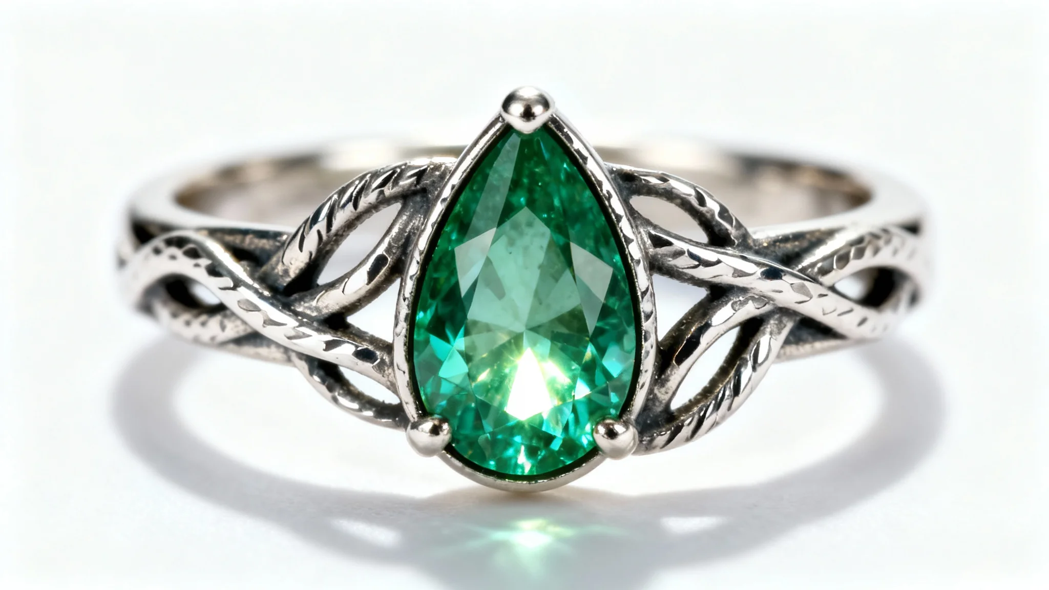 A hyper-realistic mockup image of a custom-designed sterling silver ring with a hammered texture and vine motif, featuring a central teardrop-shaped emerald, on a solid white background.