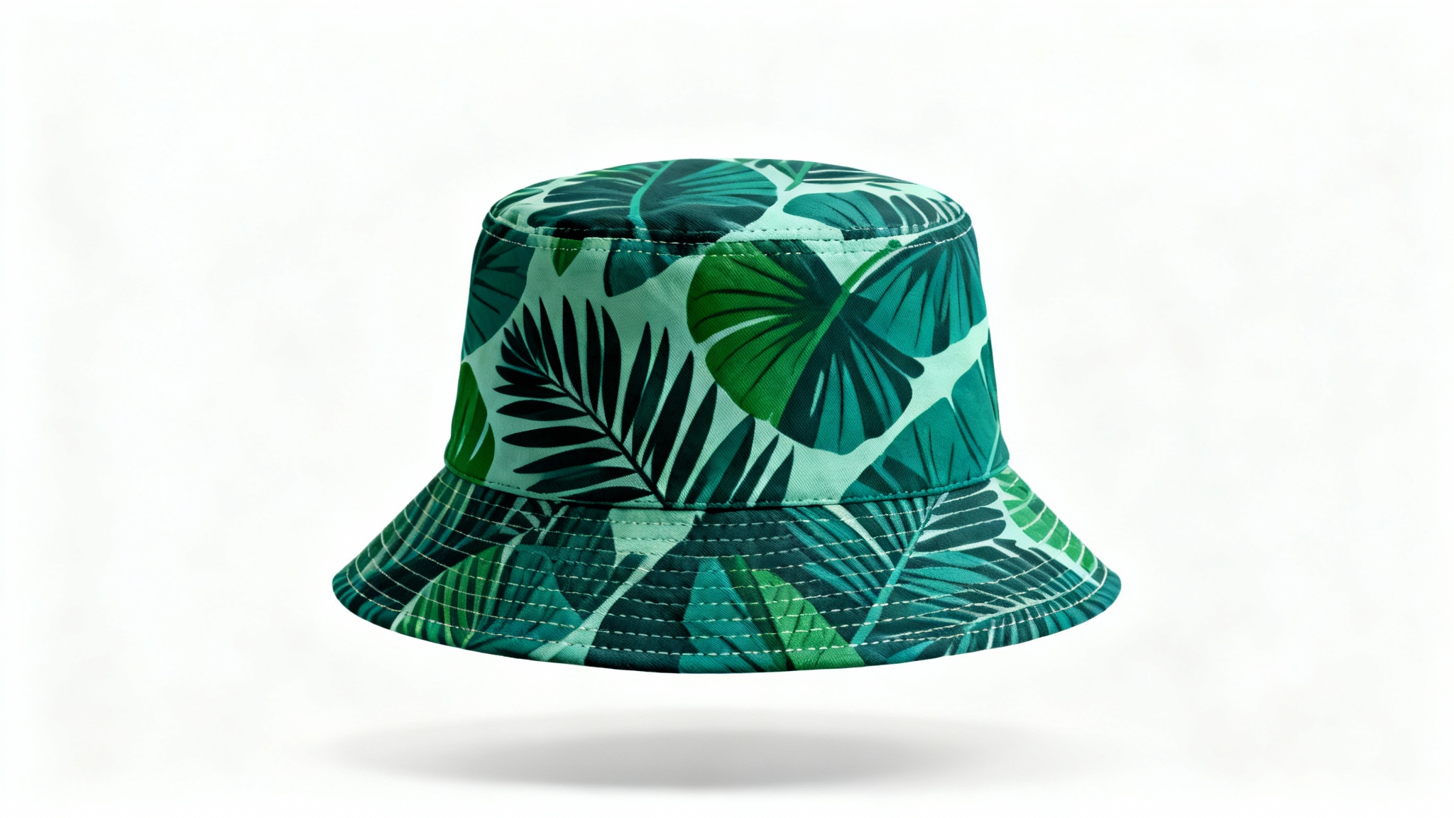 A professional product mockup of a bucket hat with a green and teal tropical leaf pattern, shown against a clean white background.