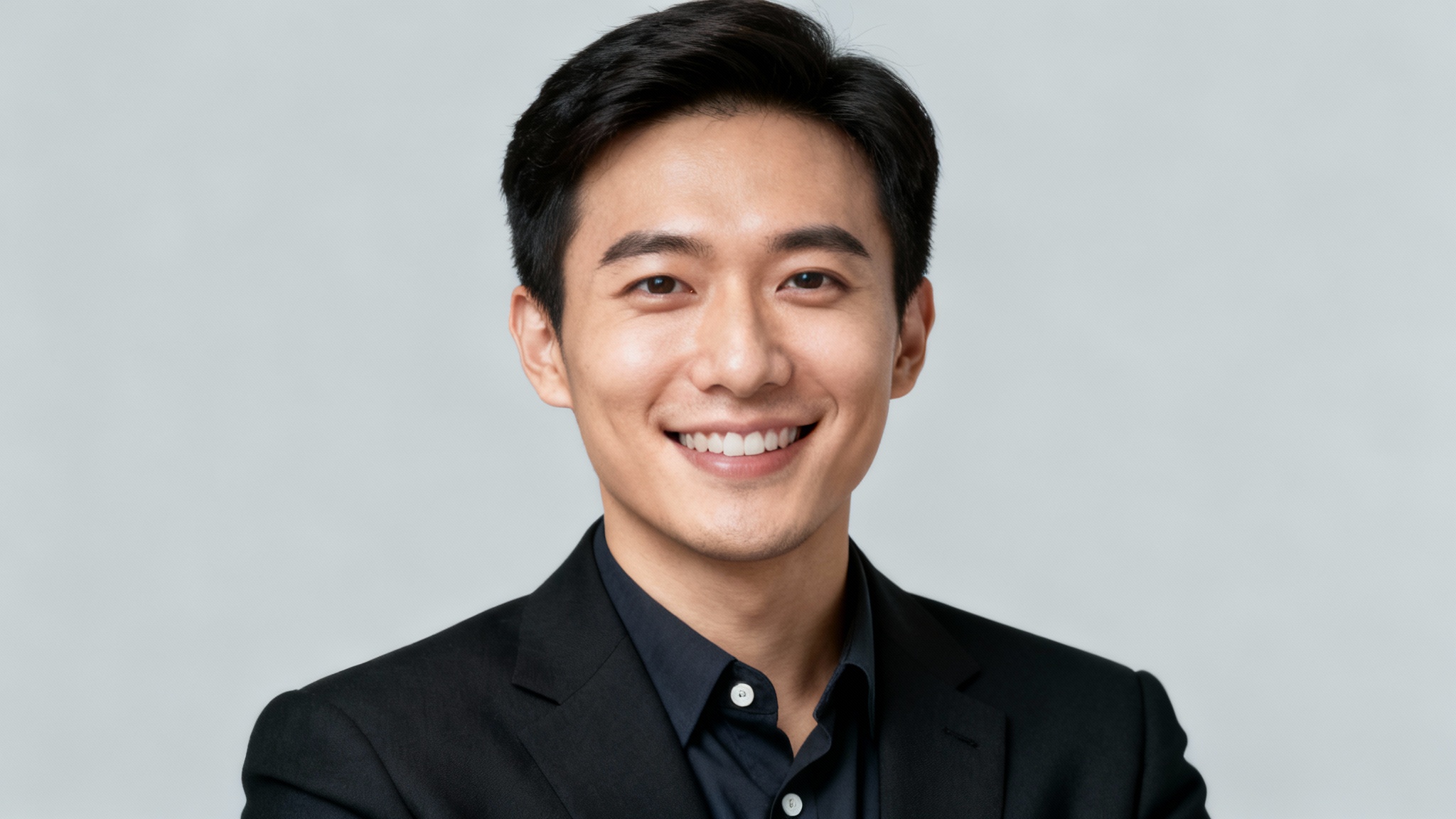 A professional LinkedIn headshot of a person smiling confidently, dressed in business attire against a clean, light grey studio background.