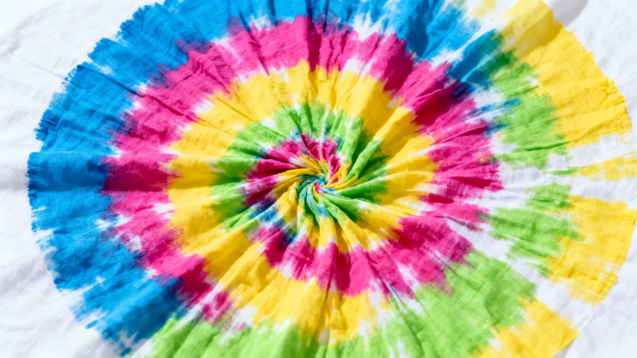 A vibrant, multi-colored spiral tie-dye pattern on a flat piece of fabric, set against a clean white background.