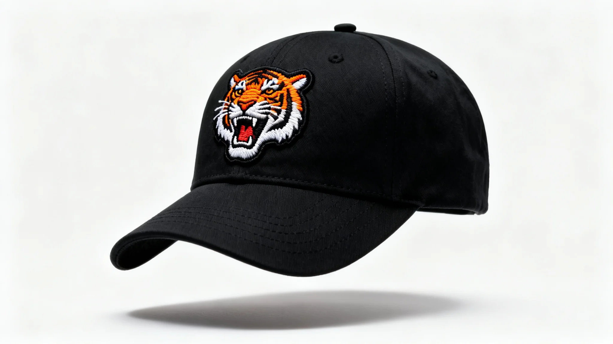 A photorealistic mockup of a black baseball cap with a detailed embroidered patch of a roaring tiger on the front, set against a clean white background.