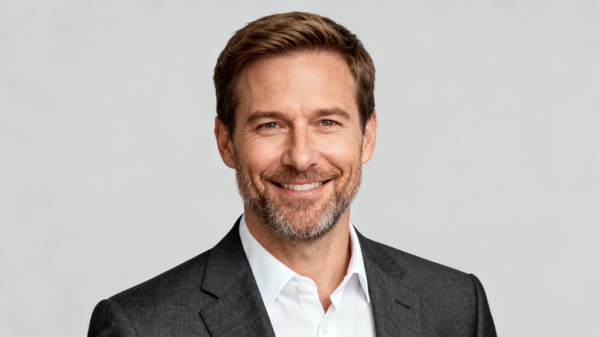 A professional, high-quality headshot of a smiling man in a suit, perfect for a LinkedIn profile picture, set against a plain background.