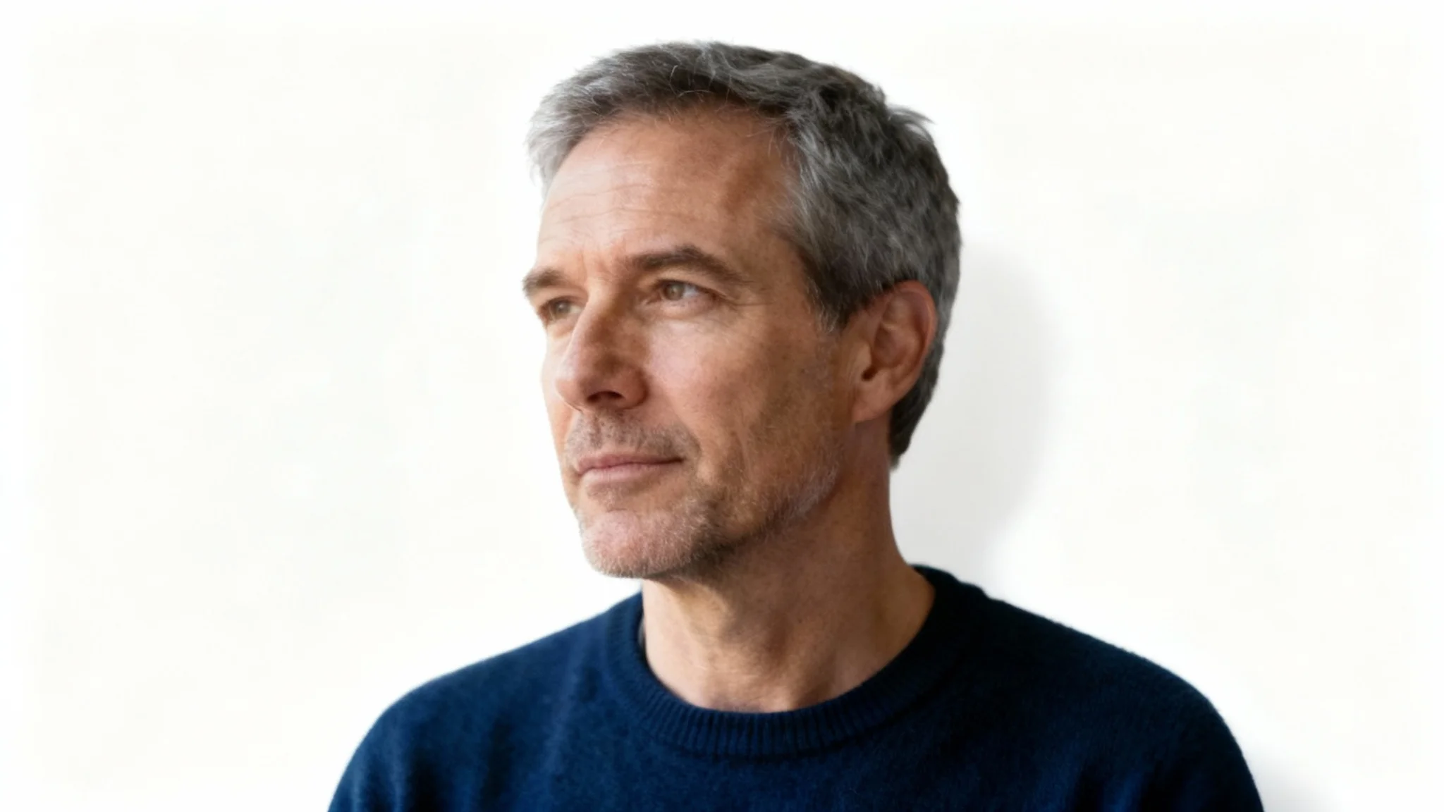 A professional photograph showing the result of a subject isolation tool: a middle-aged man in a blue sweater is perfectly cut out and placed against a clean white background.