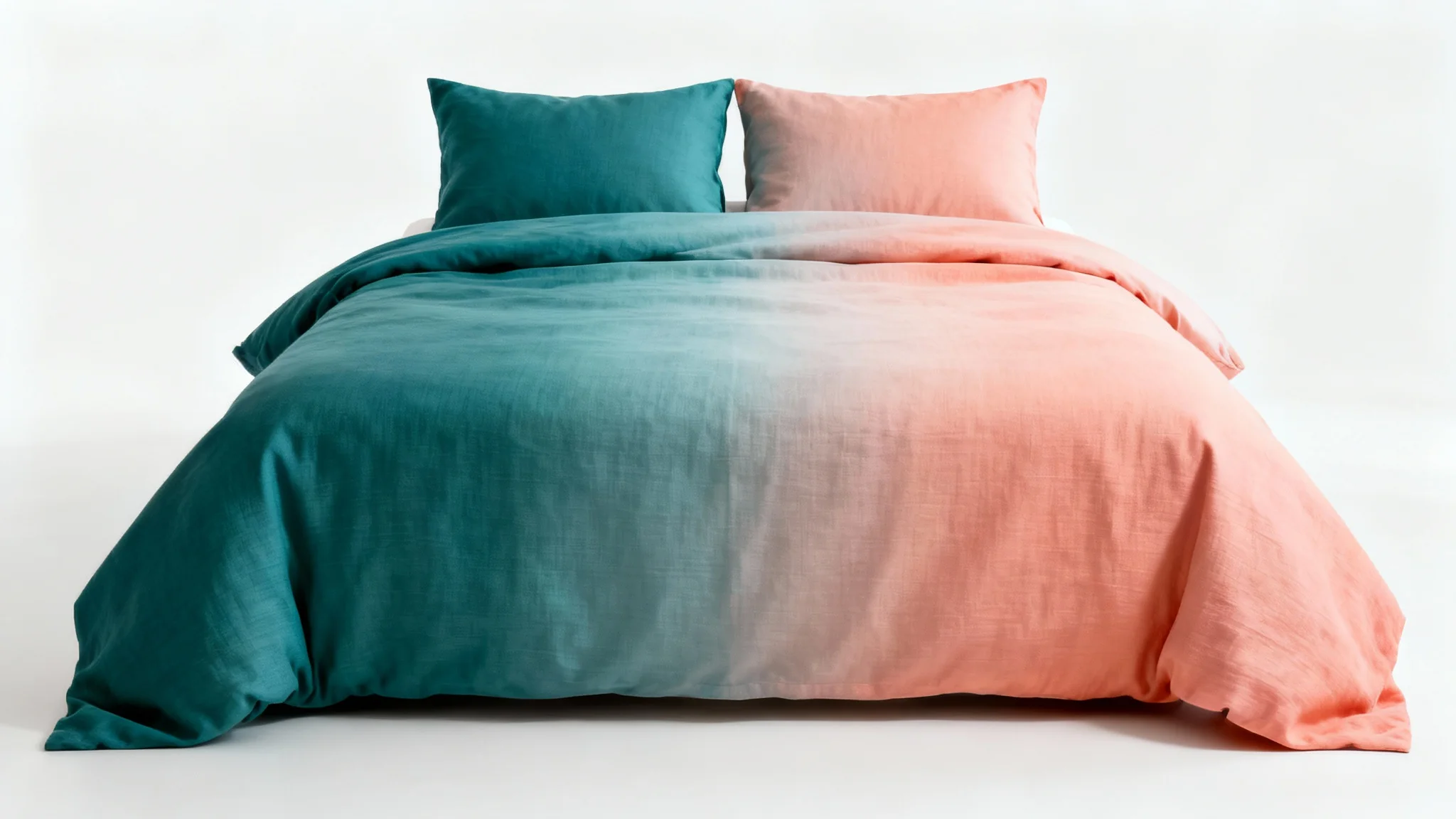 A modern bed with a duvet and pillows that smoothly transition in color from teal to coral, set against a clean white background.