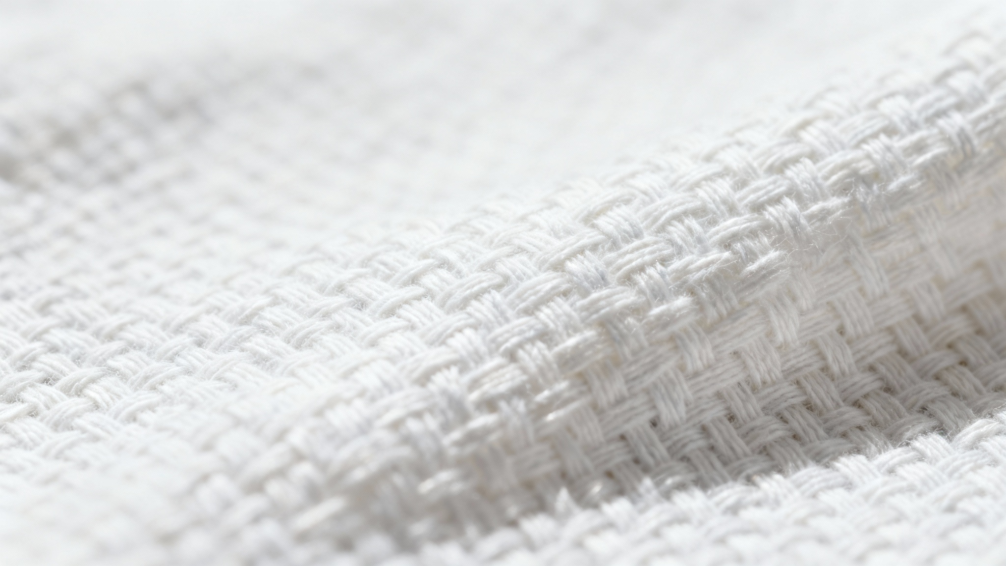 A hyper-detailed macro shot of a white cotton fabric, revealing the intricate texture of its weave and individual fibers under soft lighting.