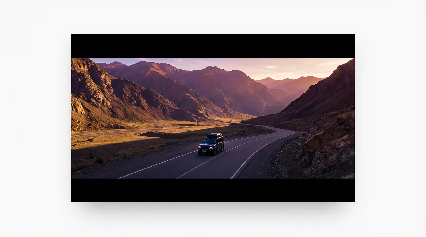 A cinematic video still presented in a letterbox format, showing a car driving through a mountain valley at sunset. The image is on a clean white background, illustrating a video editing feature.