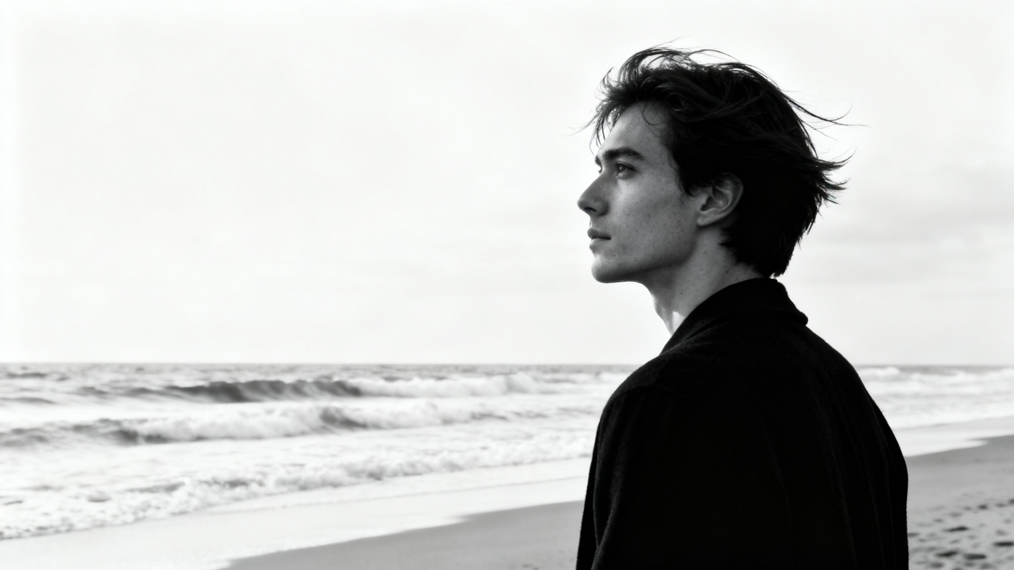 A dramatic black and white portrait of a person on a beach looking out at the ocean, presented on a white background.