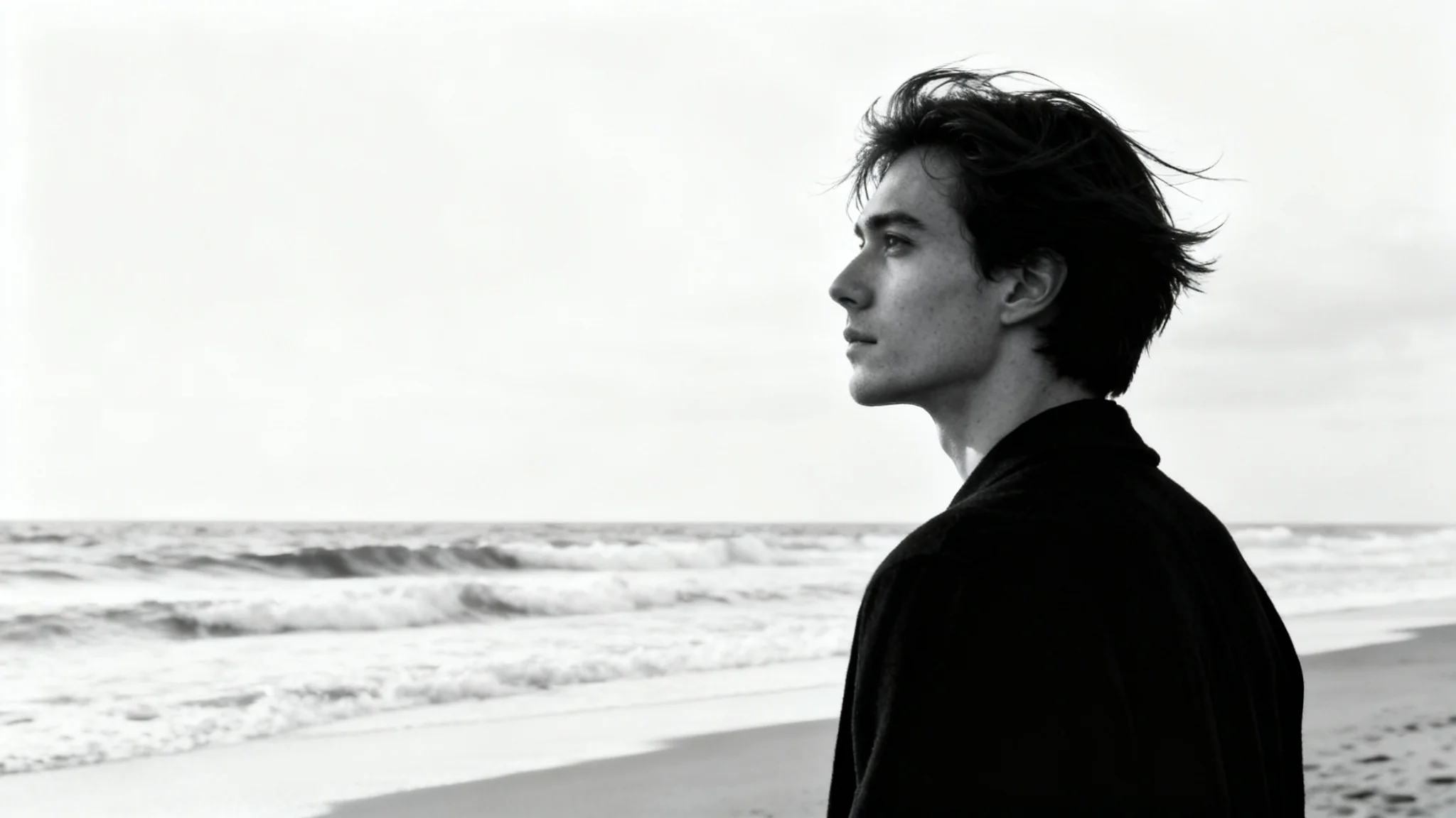 A dramatic black and white portrait of a person on a beach looking out at the ocean, presented on a white background.