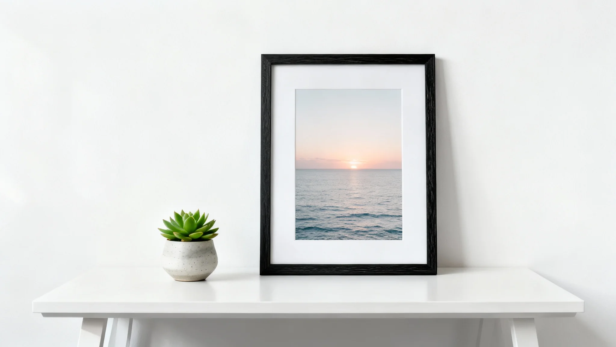 A modern black desk frame mockup standing on a clean white desk, with a small succulent plant next to it, against a plain white background.