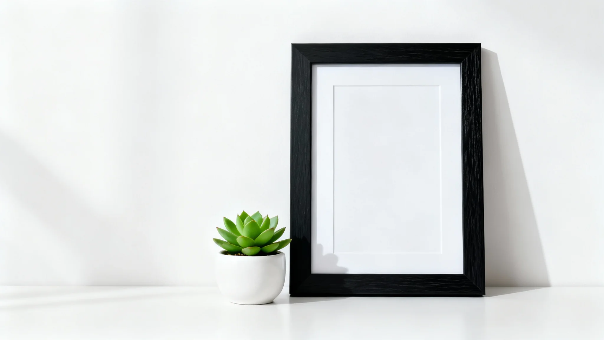 A sleek black desk frame mockup standing vertically on a white desk next to a small succulent, against a clean white background.