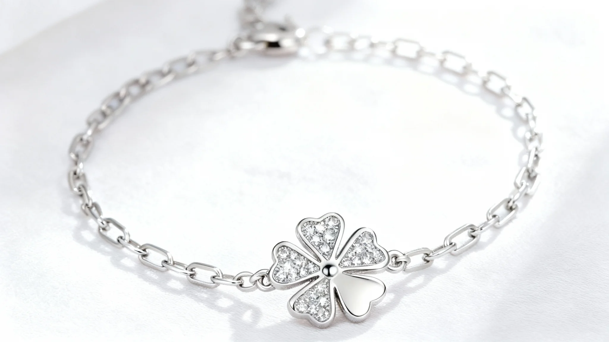 A high-end, professional product photo of a delicate silver bracelet featuring a sparkling four-leaf clover charm, displayed elegantly on a clean white background.