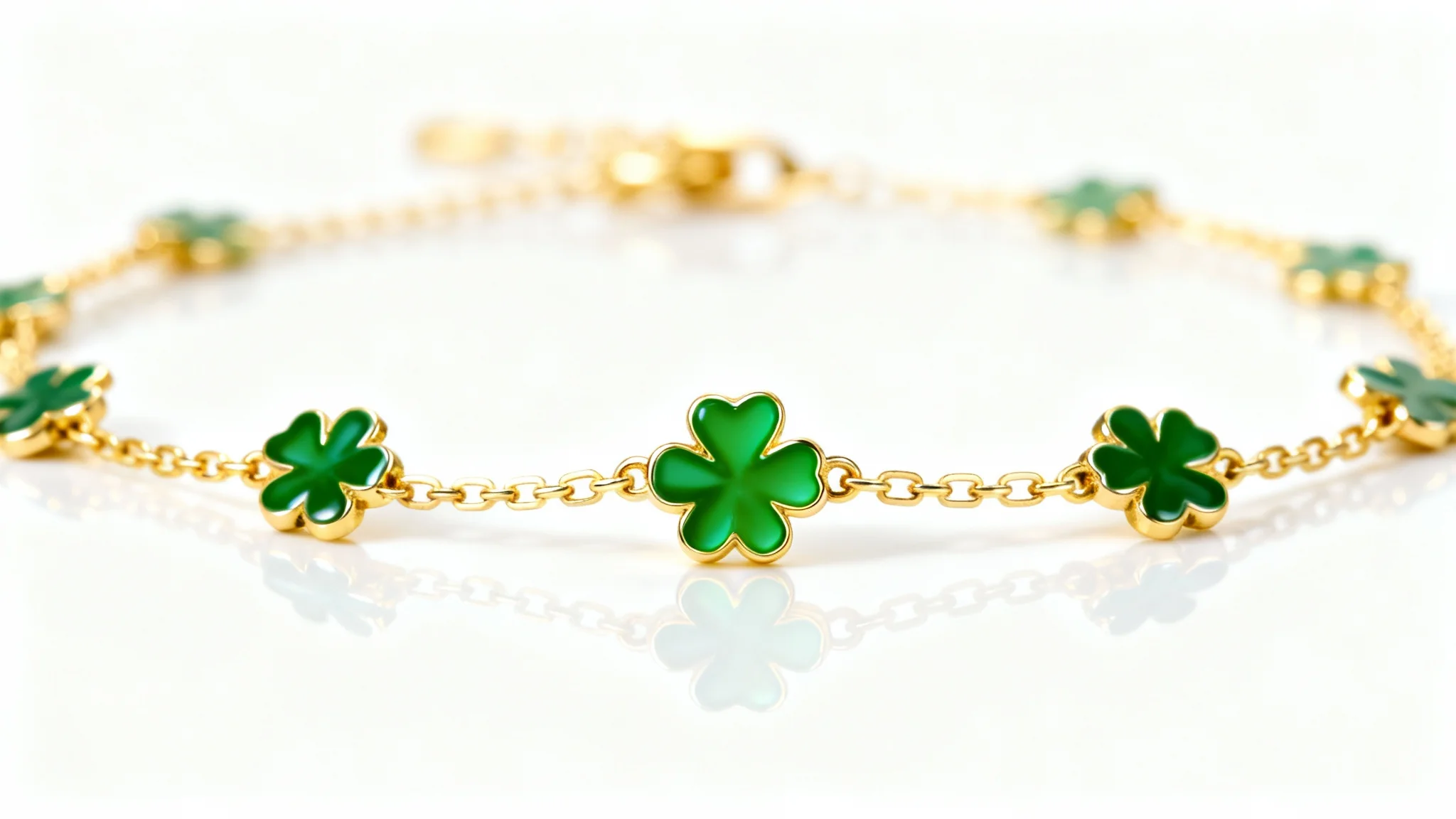 A close-up product shot of a delicate gold bracelet with small, green four-leaf clover charms on a clean white background.