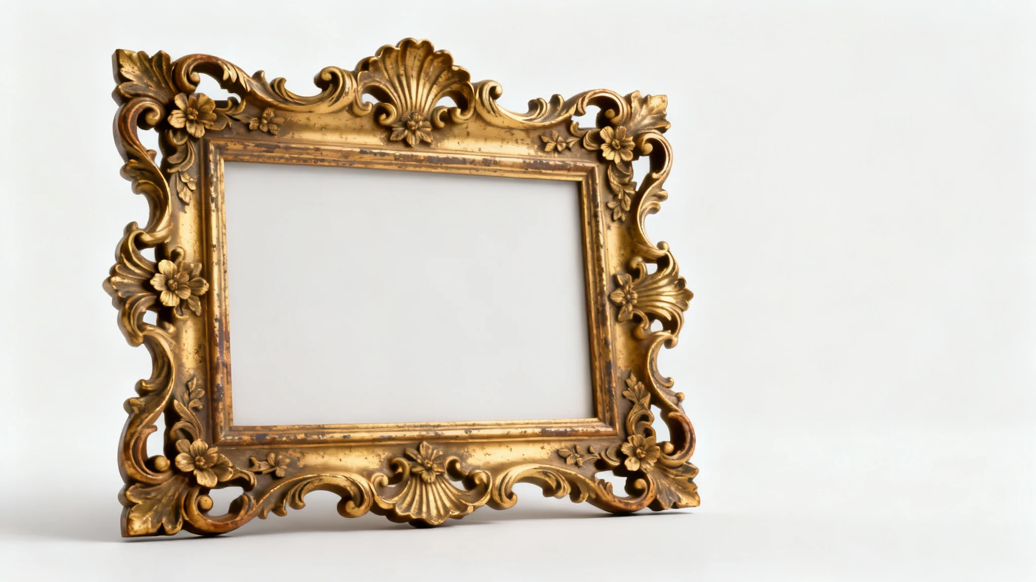 A highly detailed, empty Rococo-style picture frame with an antique gold leaf finish, featuring intricate carvings of leaves and flowers, displayed against a clean white background.