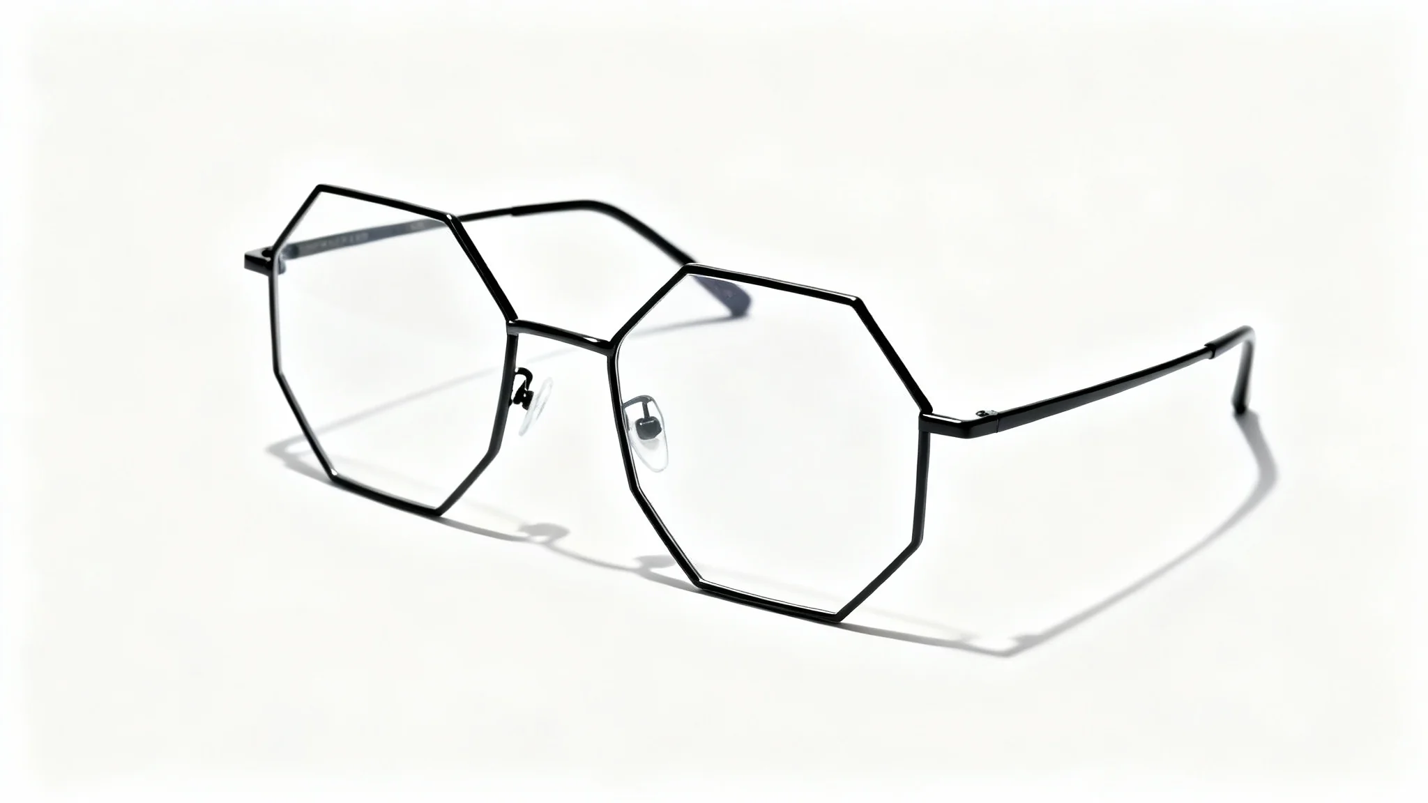 A professional product shot of a single pair of modern, minimalist eyeglasses with thin black hexagonal frames, set against a stark white background.