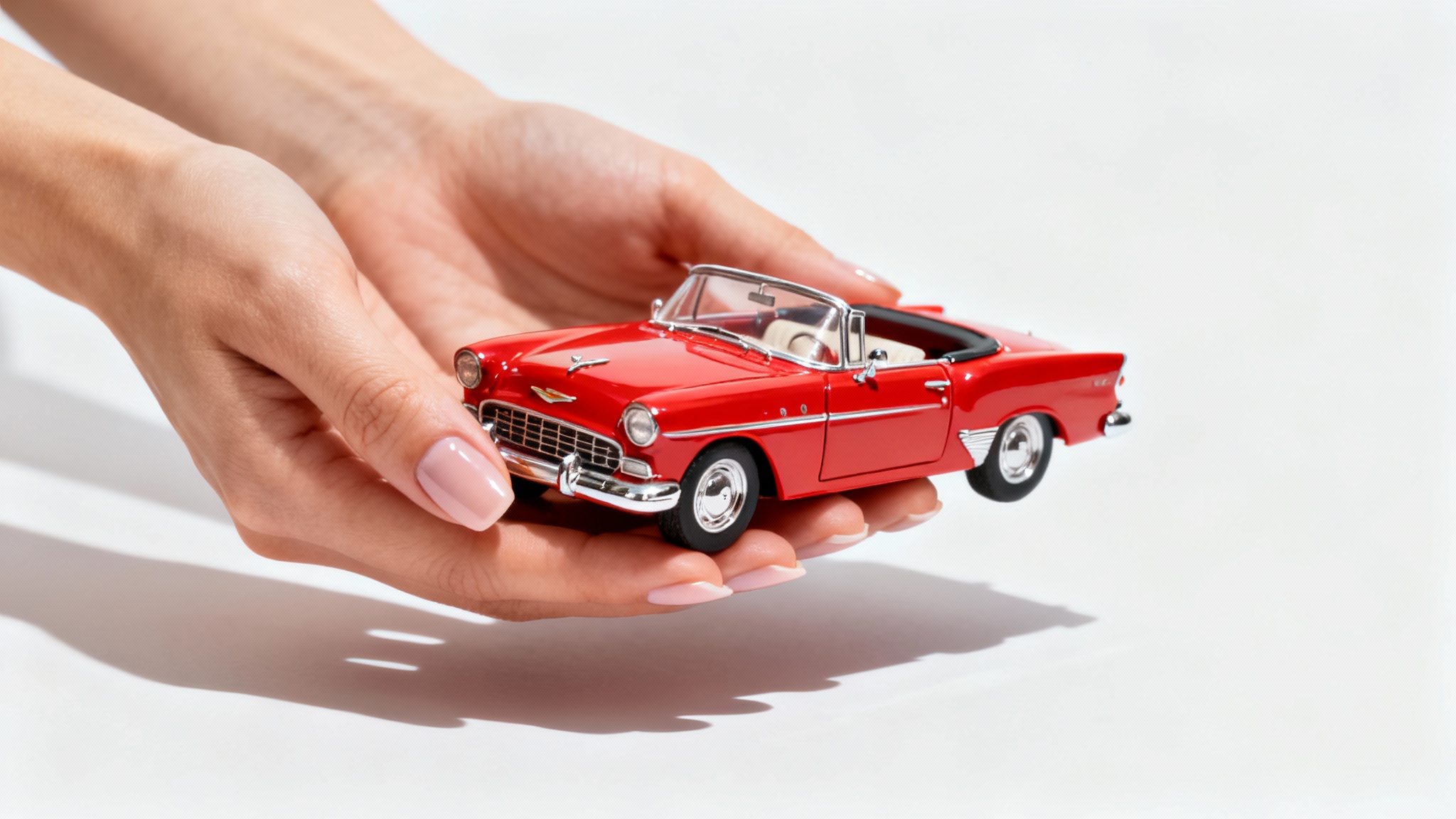 A woman's hands hold a tiny red classic car, demonstrating size illusion photography against a plain white background.