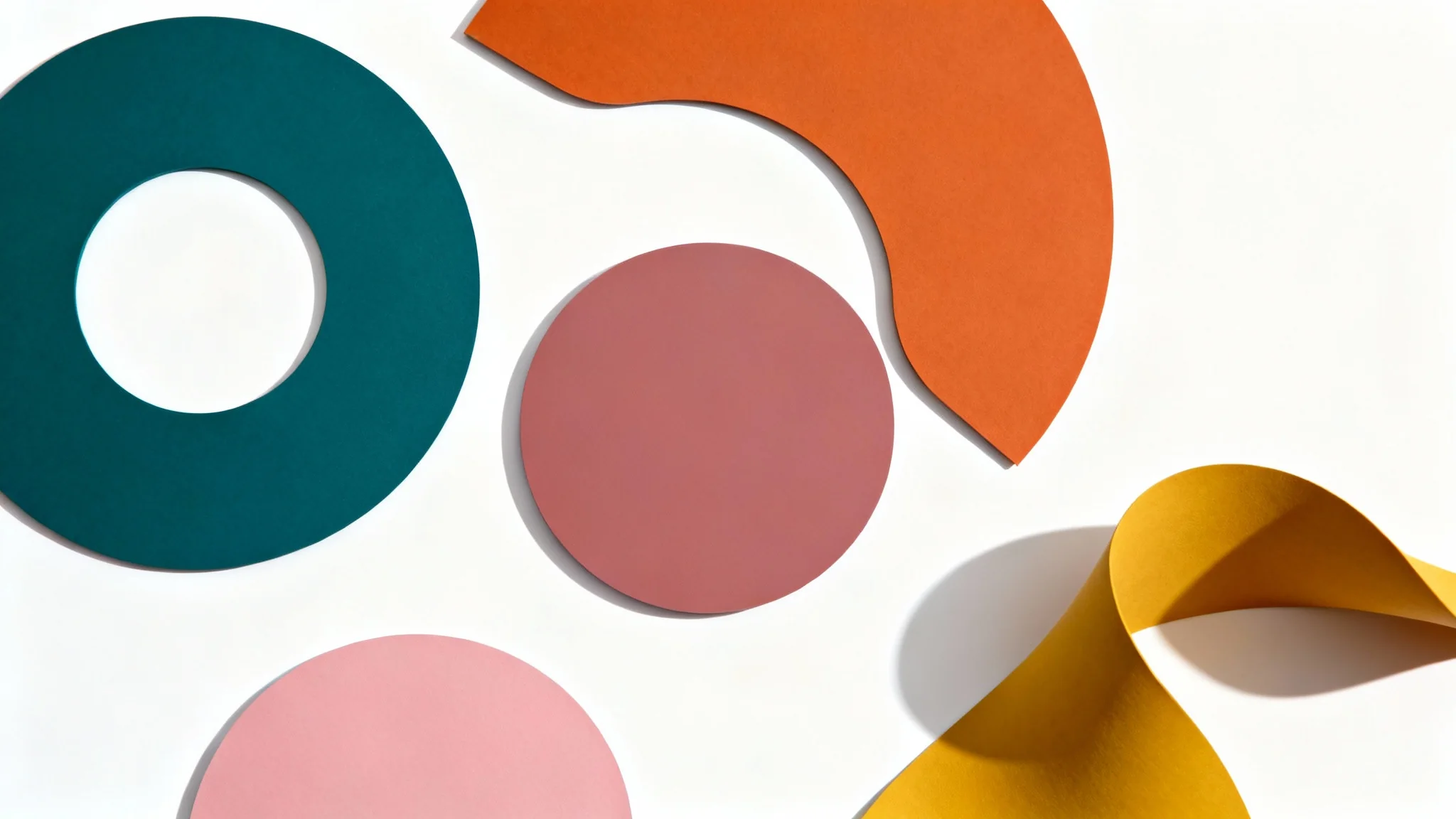 A collection of geometric and organic shapes in a harmonious color palette of teal, burnt orange, and dusty rose, arranged on a white background to illustrate color harmony.