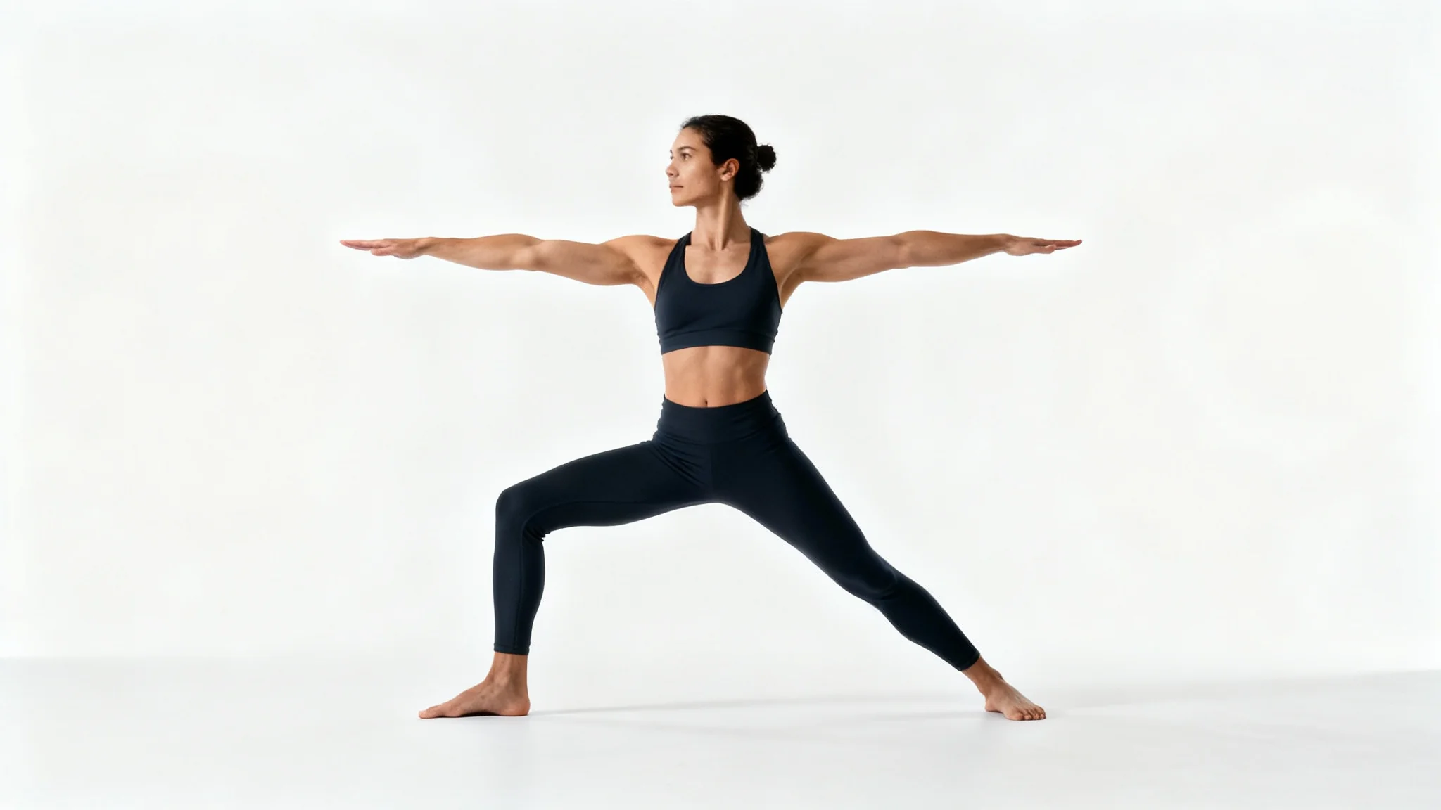 A full-body photograph of an athletic person executing a flawless Warrior II yoga pose against a stark white background, demonstrating proper form and strength.
