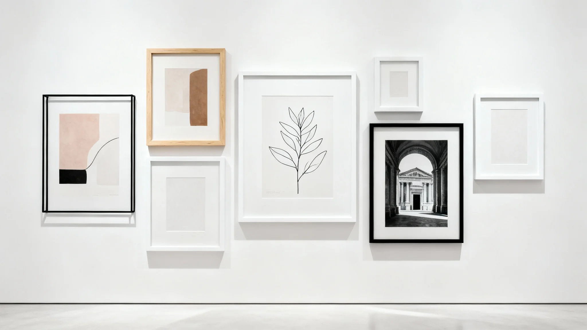 A mockup of a modern gallery wall featuring a mix of black, white, and wood frames with abstract and botanical art, displayed against a clean white background.