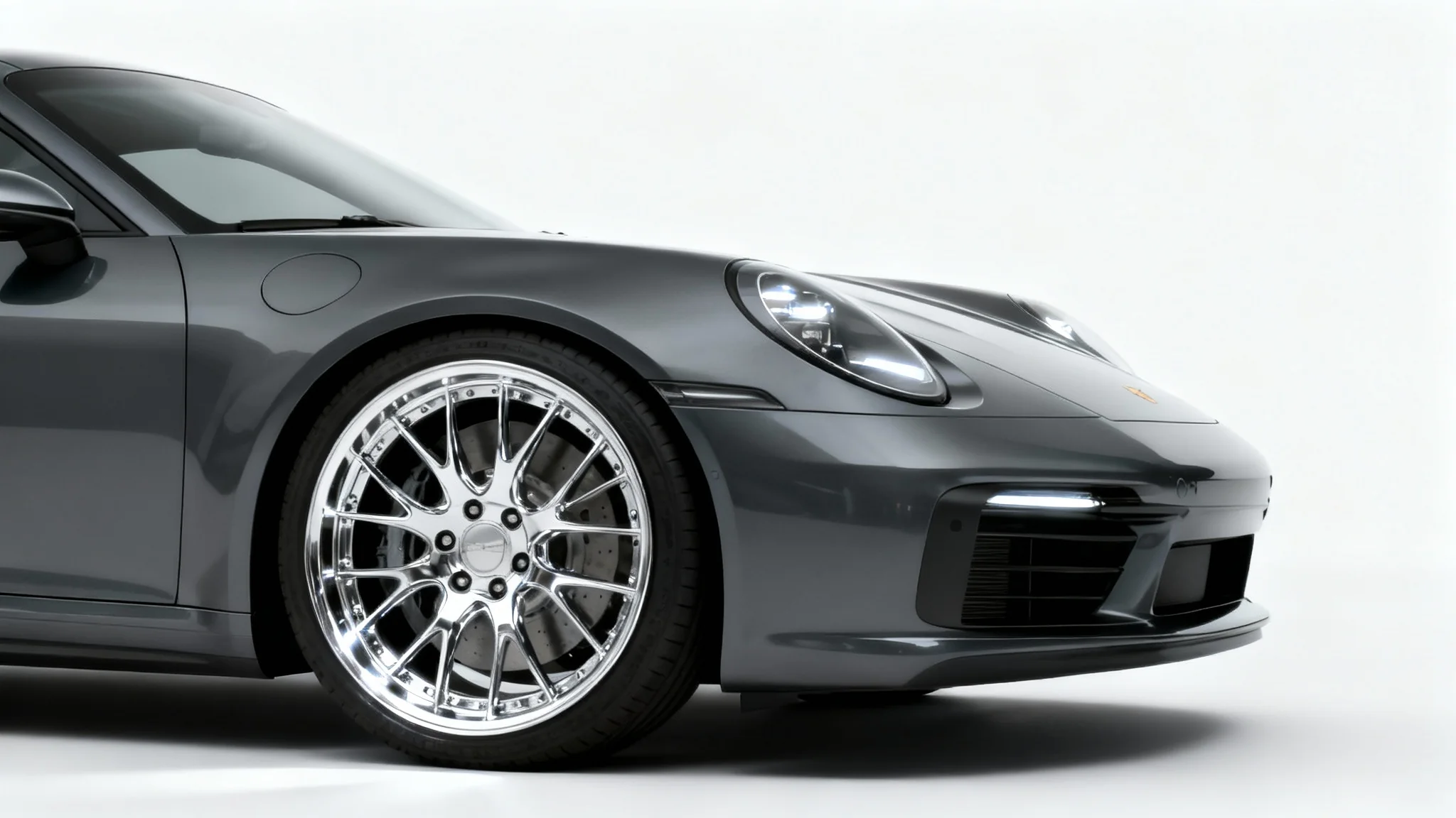 A photorealistic image of a sleek charcoal grey sports car with large, shiny chrome rims, presented as a mockup against a plain white background.